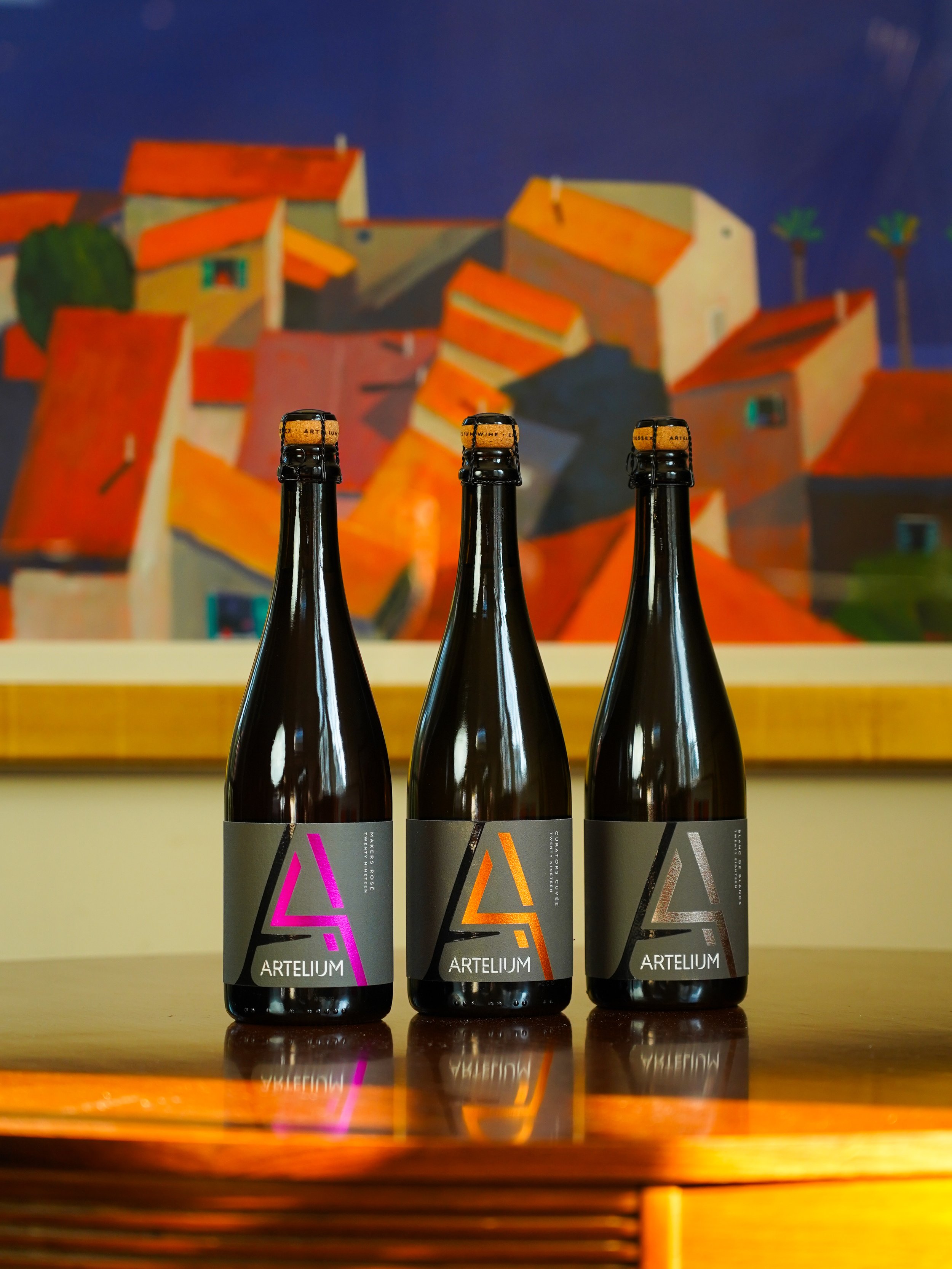 Artelium Makers Rosé Curators Cuvée & Blanc de Blancs in front of colourful painting