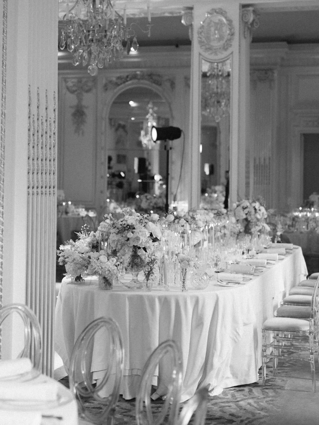 Timeless in white. Round tables dressed in lush ivory florals, roses, ranunculus, and delicate greenery &mdash; set against the gilded grandeur of the Mandarin Oriental. Ghost chairs keep the look effortlessly modern while the candlelight does the re