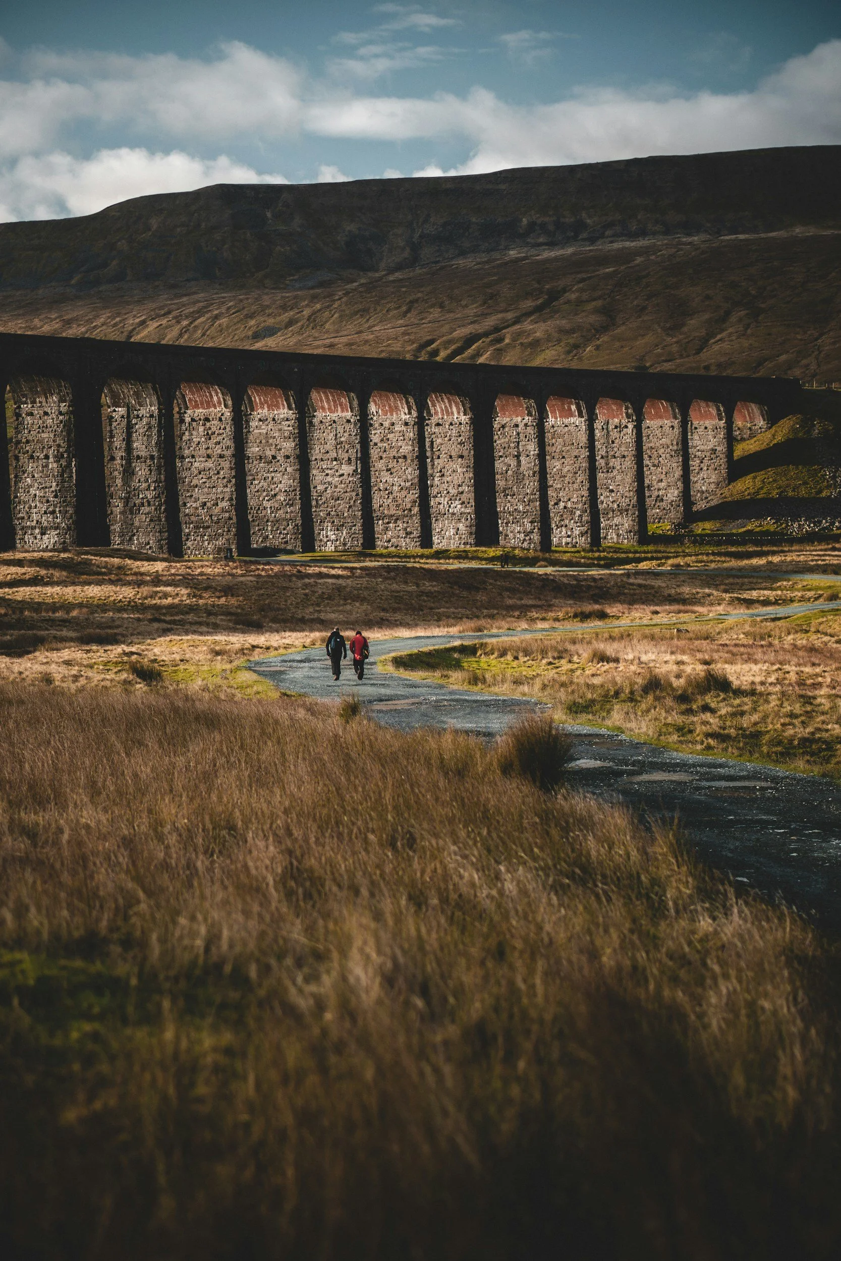 hikers walking towards ribbleshead viaduct on the yorkshire three peaks challenge