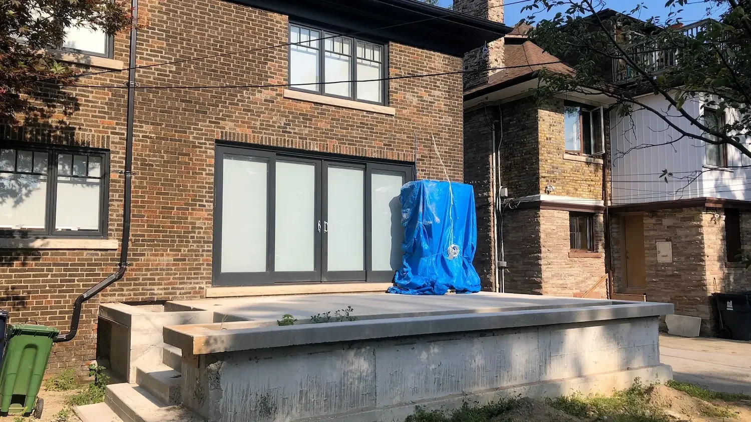 Poured concrete patio foundation and steps at brick home in Roncesvalles, Toronto by Odin Agnuk