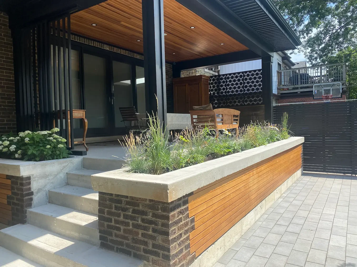 Completed cedar covered patio with built-in planter and sliding privacy screen in Roncesvalles by Odin Agnuk