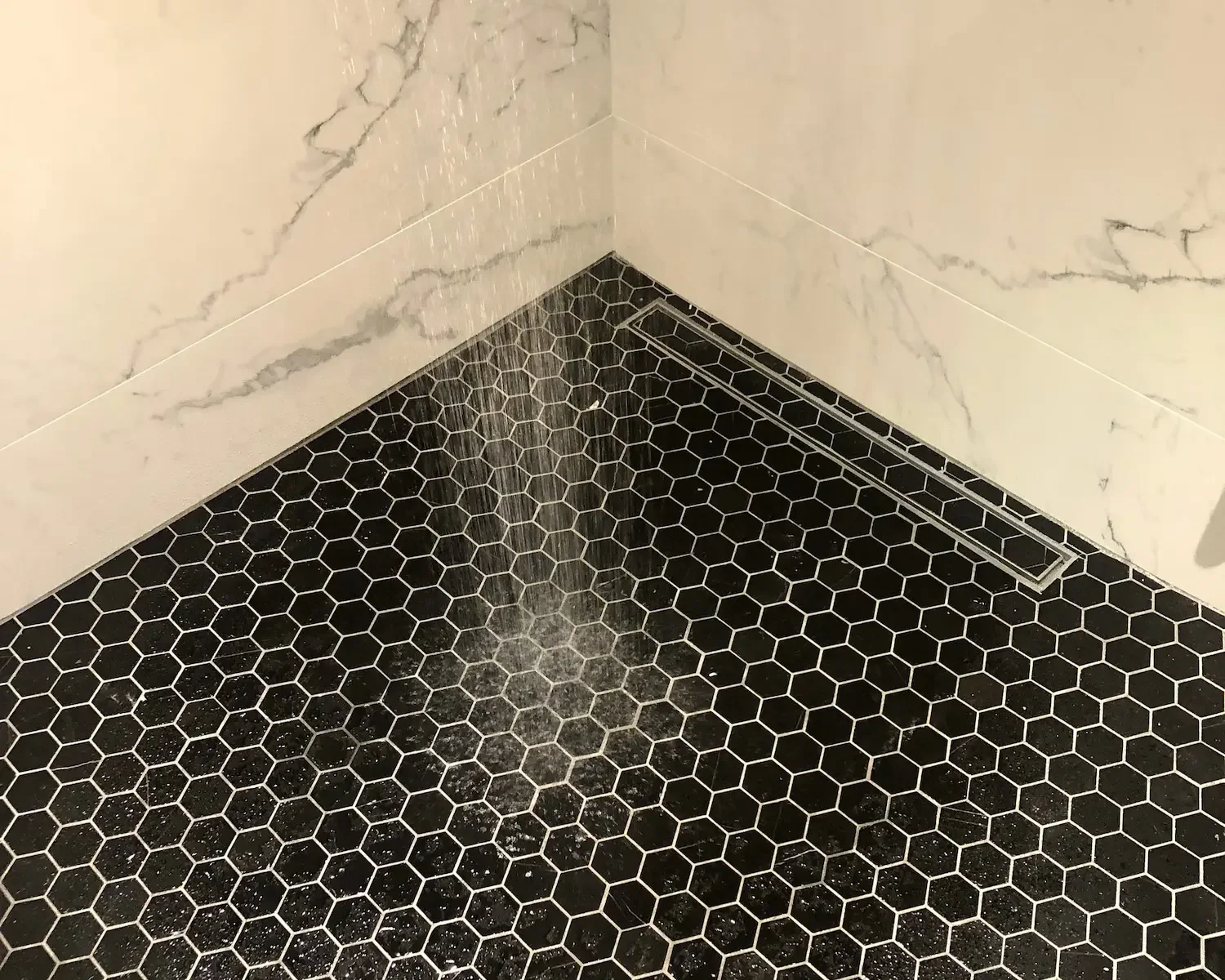 Black hexagon tile shower floor with linear drain - The Beaches Toronto bathroom renovation by Odin Agnuk