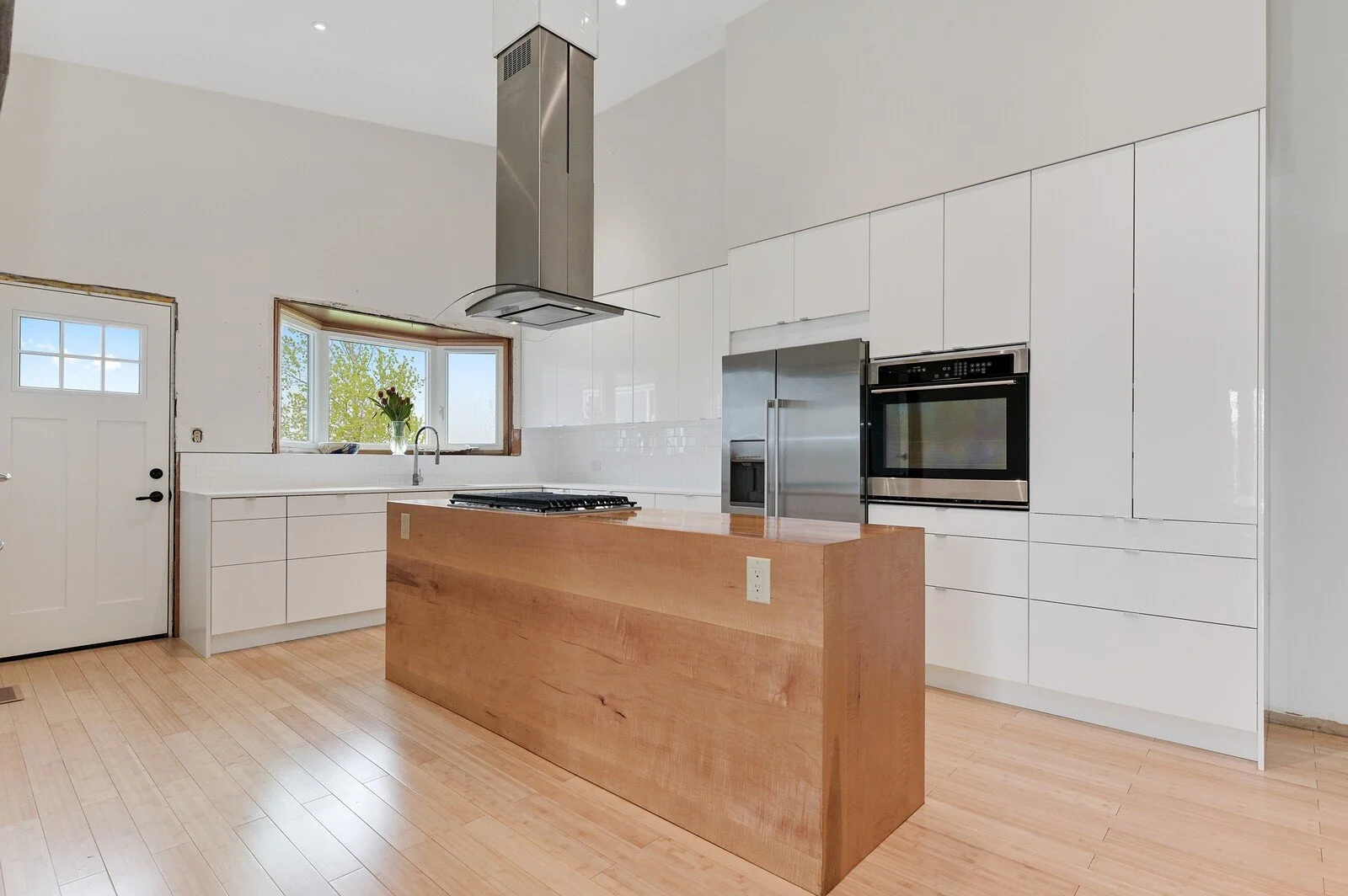 Modern kitchen with high gloss white cabinets and custom maple waterfall island - Grey County by Odin Agnuk
