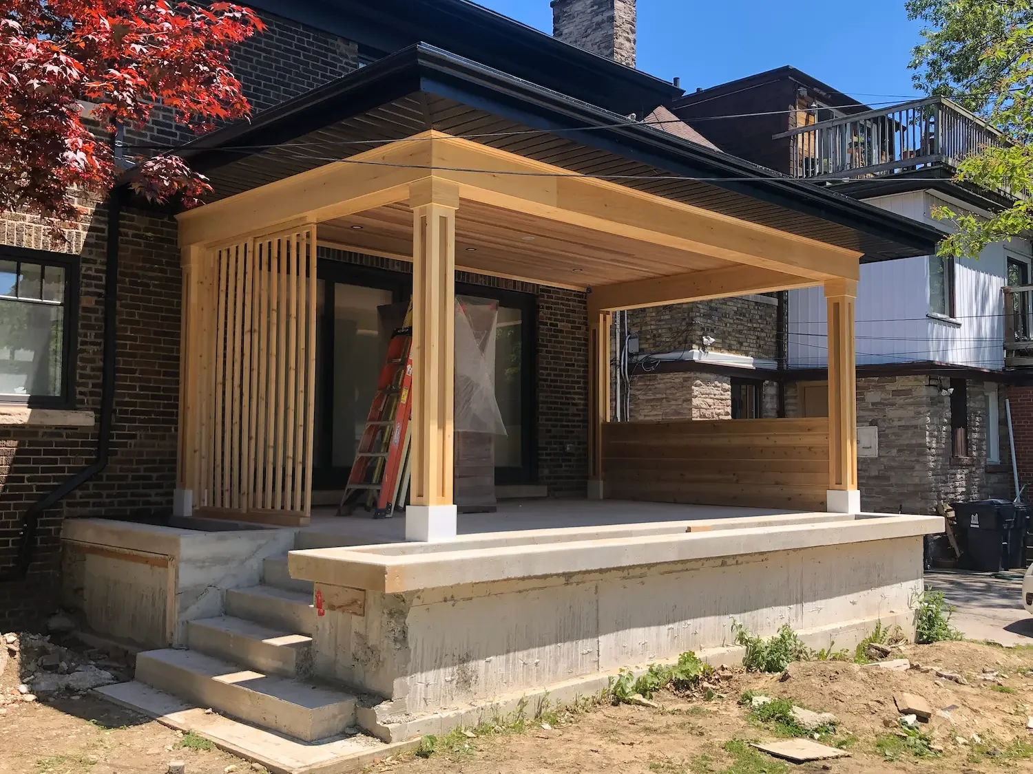 Covered patio with cedar ceiling and vertical slat privacy screen in progress in Roncesvalles, Toronto by Odin Agnuk