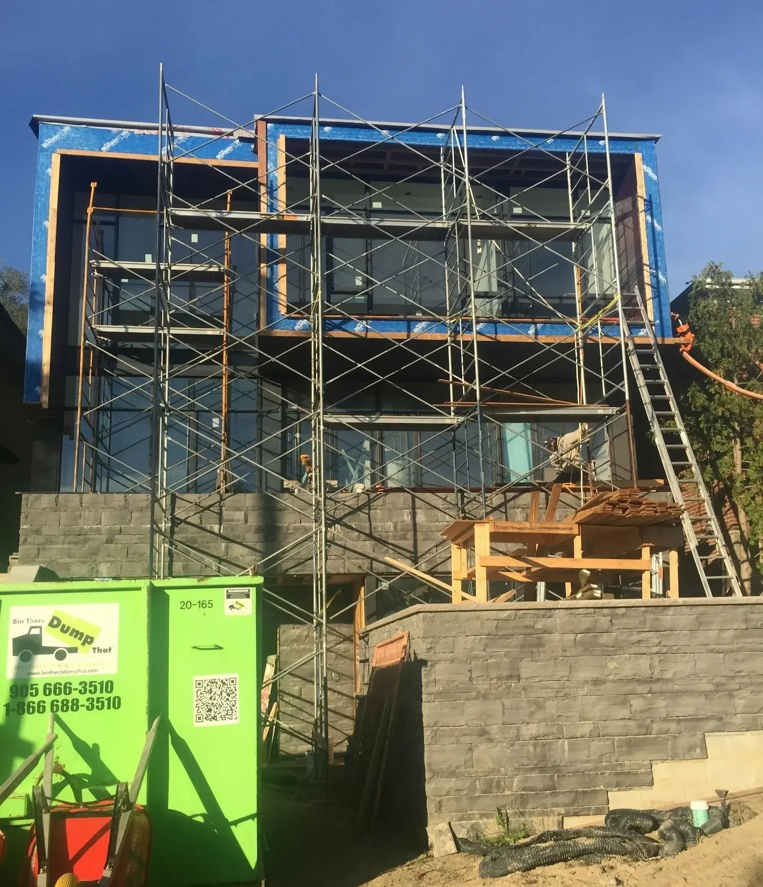 Custom home exterior with ipe siding and full height windows under construction by Odin Agnuk