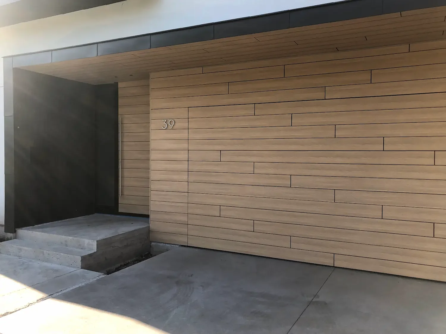 Front entry and garage doors with horizontal Trespa Pura NFC cladding and soffit detail at Scarborough Bluffs home by Odin Agnuk