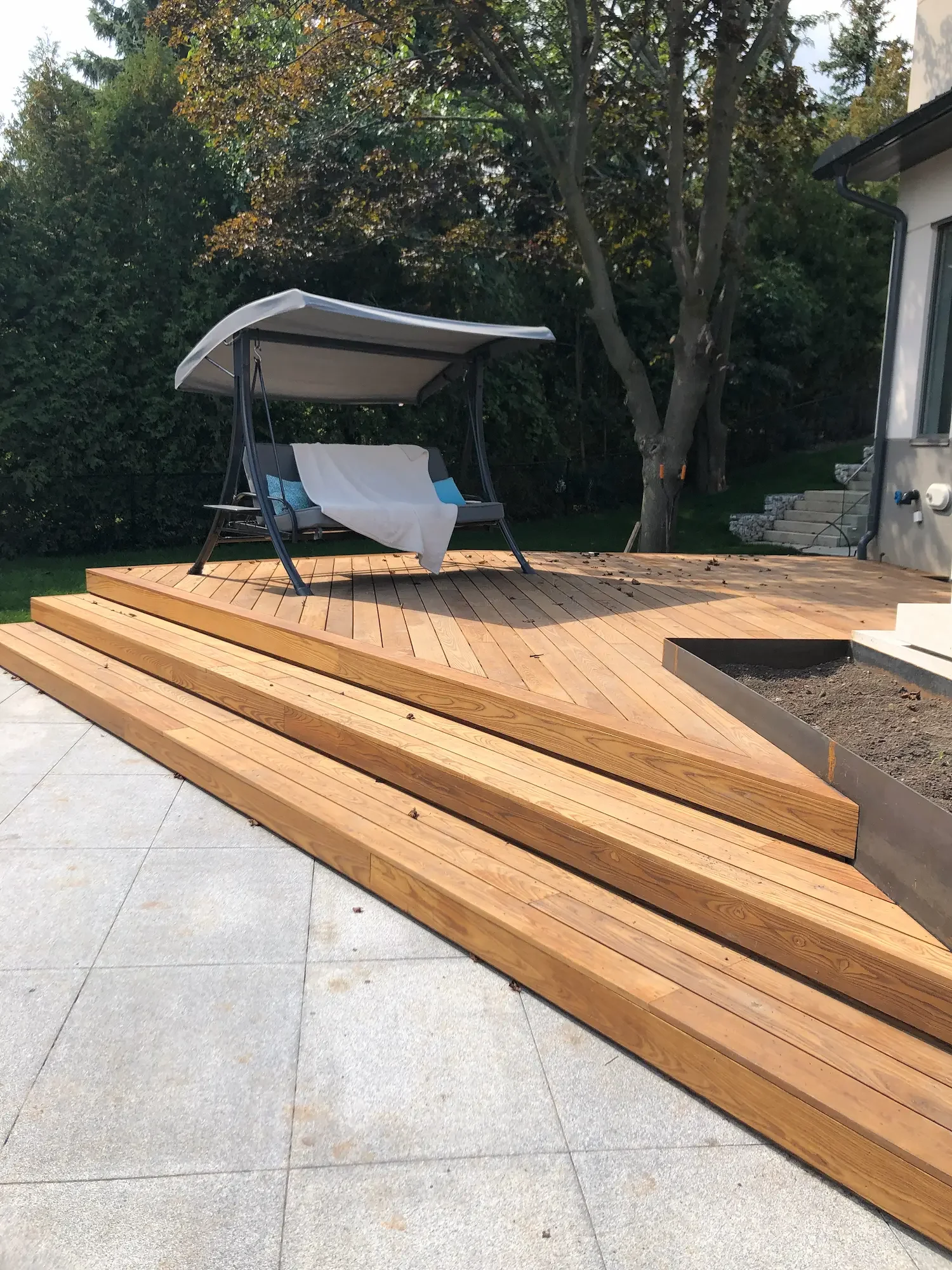 Thermory ash deck corner stairs meeting stone patio in Brant Hills Burlington by Odin Agnuk