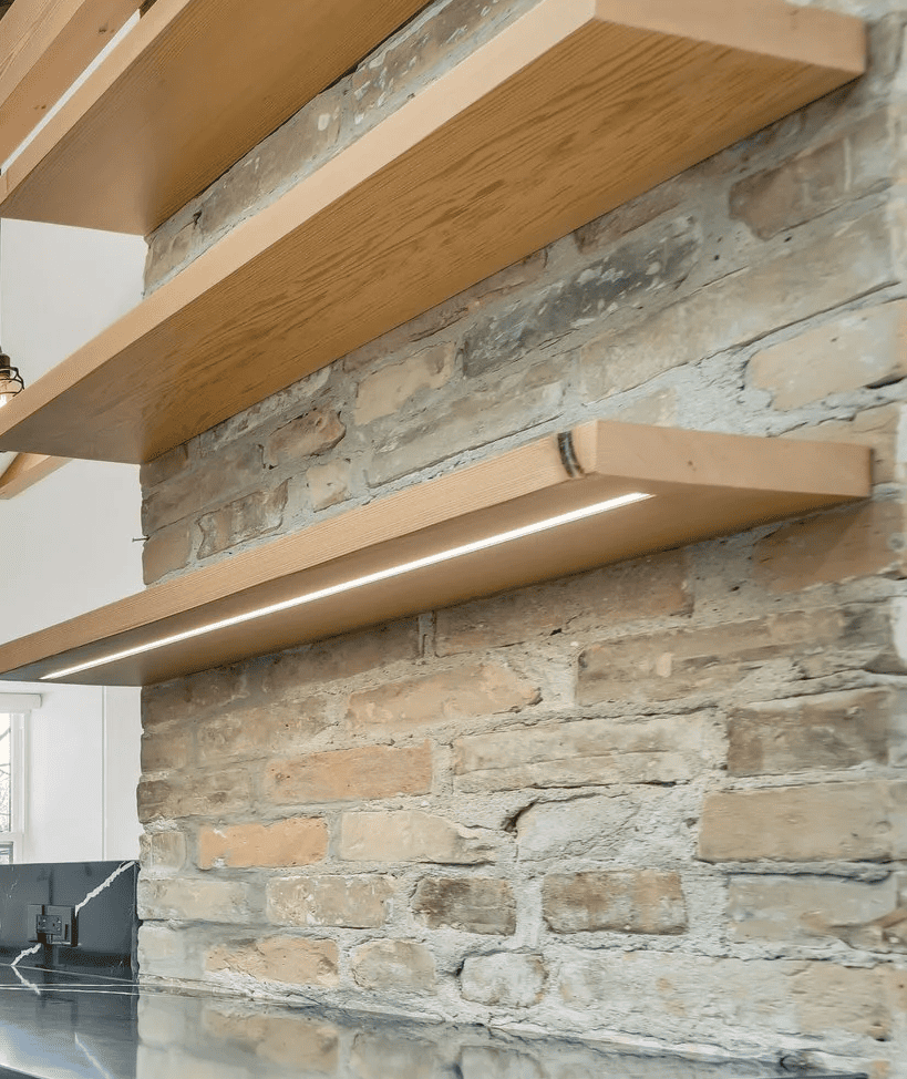 Fir floating shelves with integrated LED lighting against exposed brick wall in Guelph kitchen renovation by Odin Agnuk