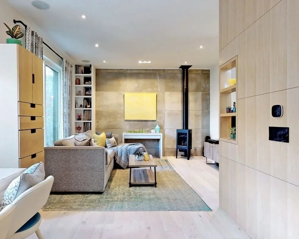 Living room with concrete wall wood stove and custom built-in cabinetry at home in The Pocket, Toronto by Odin Agnuk