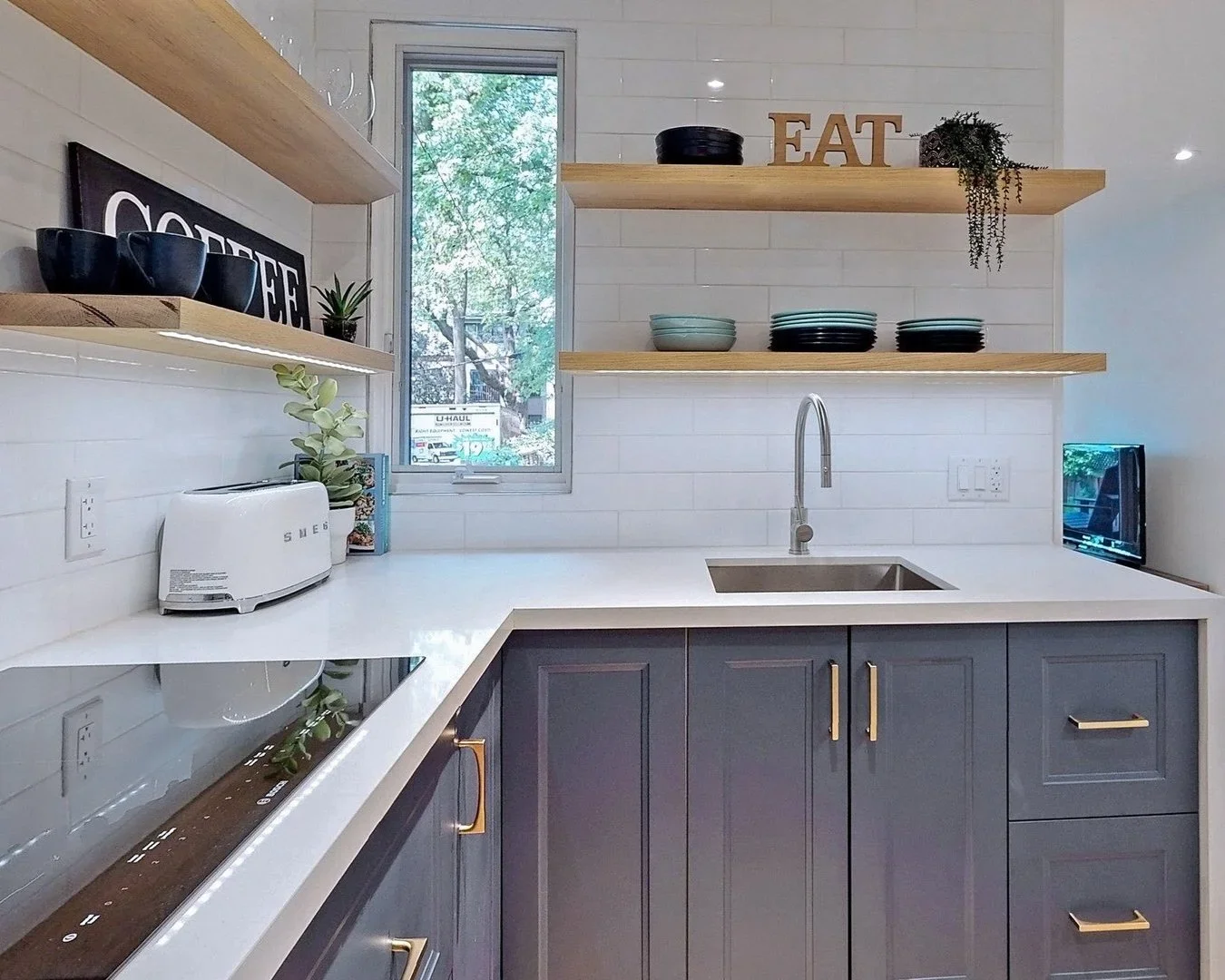Kitchen renovation with white subway tile backsplash blue cabinets floating oak shelves and quartz counters by Odin Agnuk