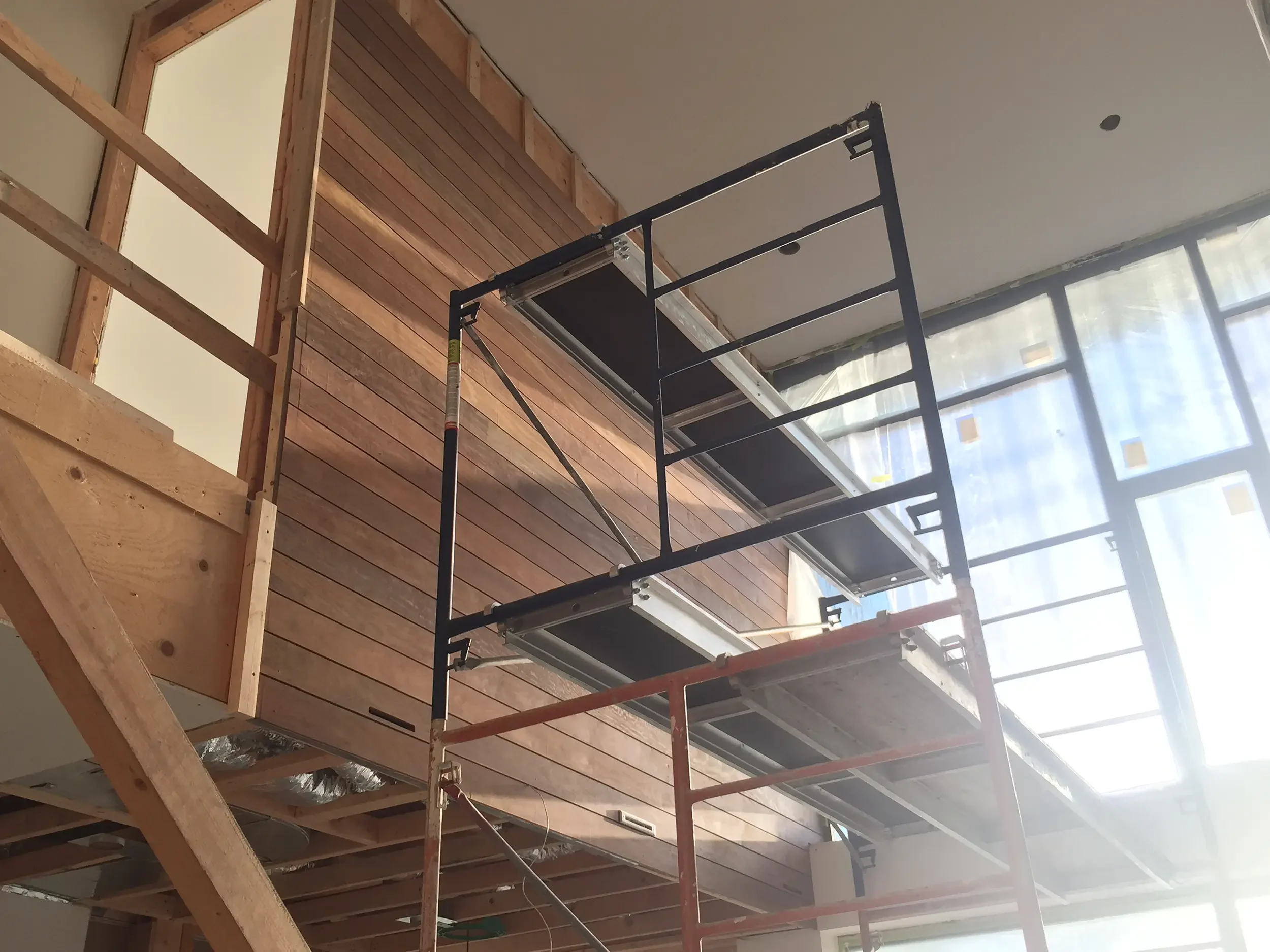 Interior ipe wood siding feature wall installation with scaffolding in custom home Toronto by Odin Agnuk