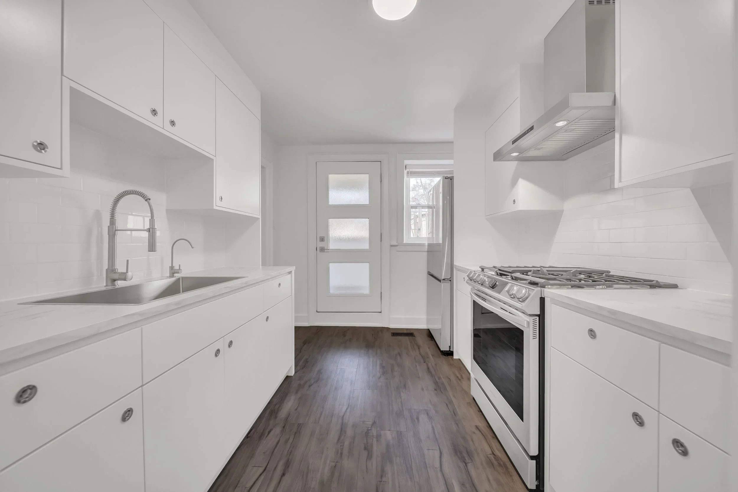 Galley kitchen renovation with white cabinets subway tile backsplash and quarts countertops in Guelph by Odin Agnuk
