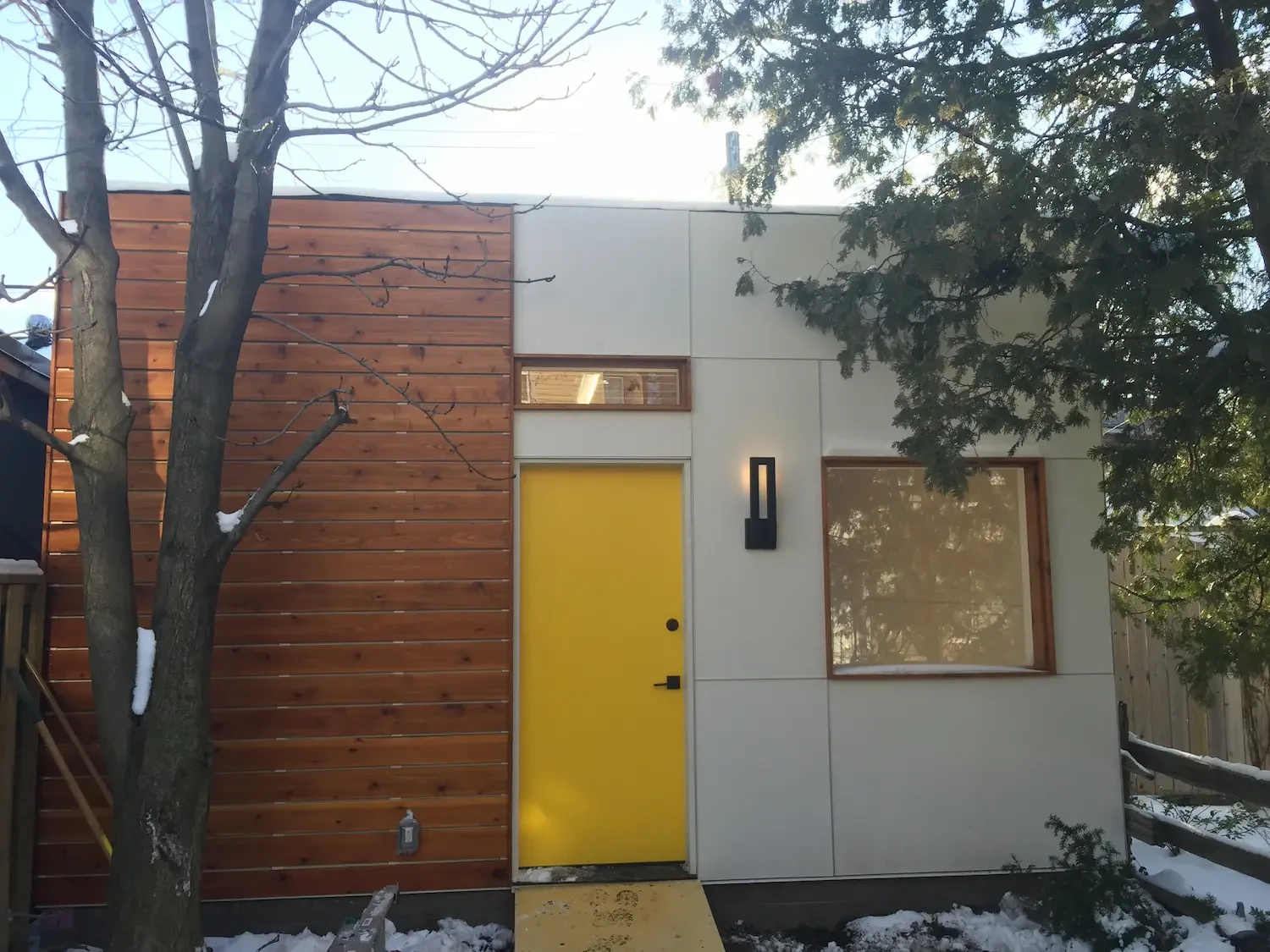 Garage with panel cladding cedar siding and yellow door in Toronto by Odin Agnuk