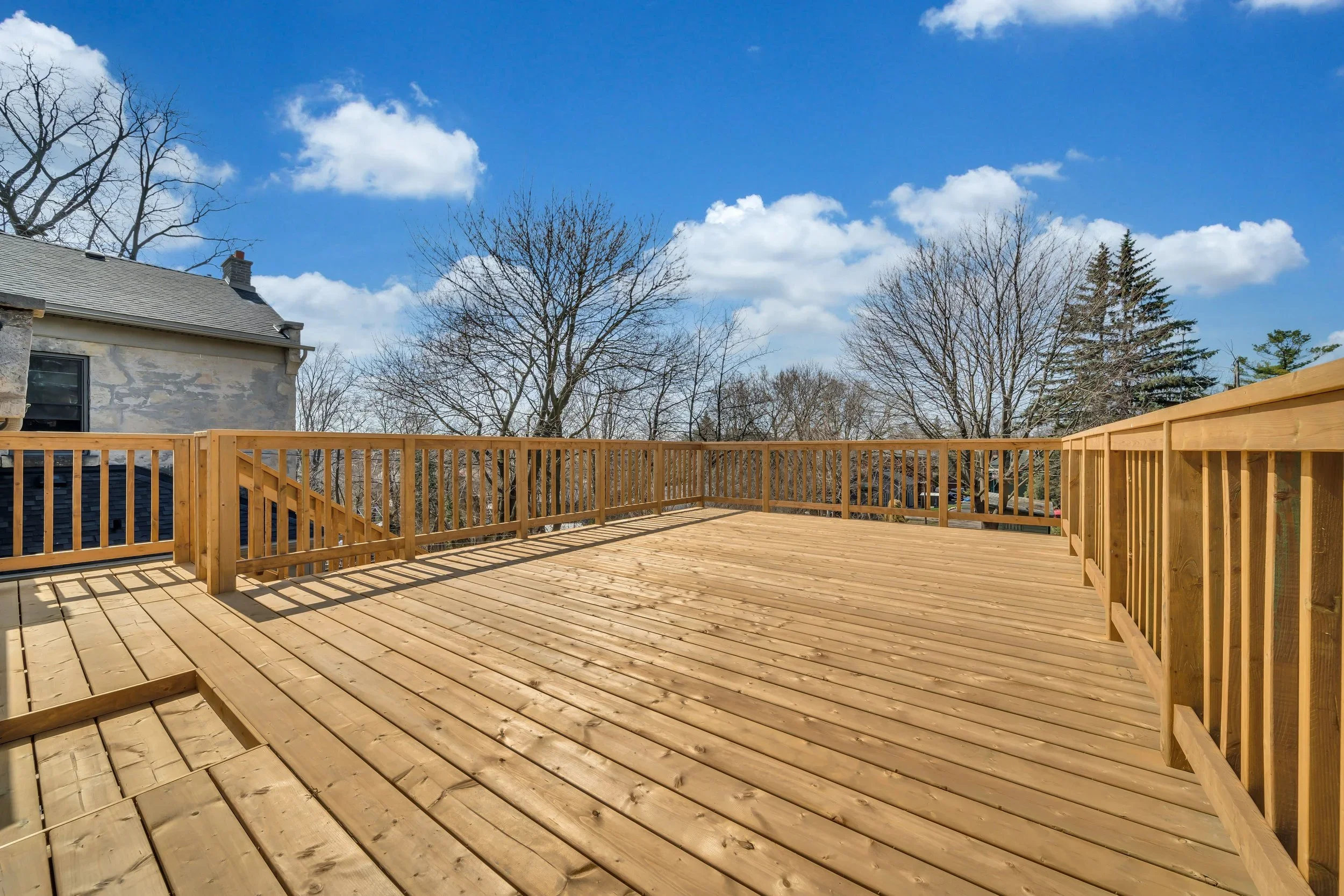 Large pressure-treated roof top wood deck with custom wood railing in Guelph century home renovation by ODIN+AGNUK