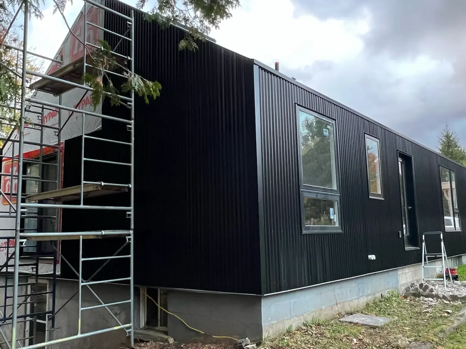 Black vertical corrugated metal siding installation in progress at Beaver Valley custom home build by Odin Agnuk