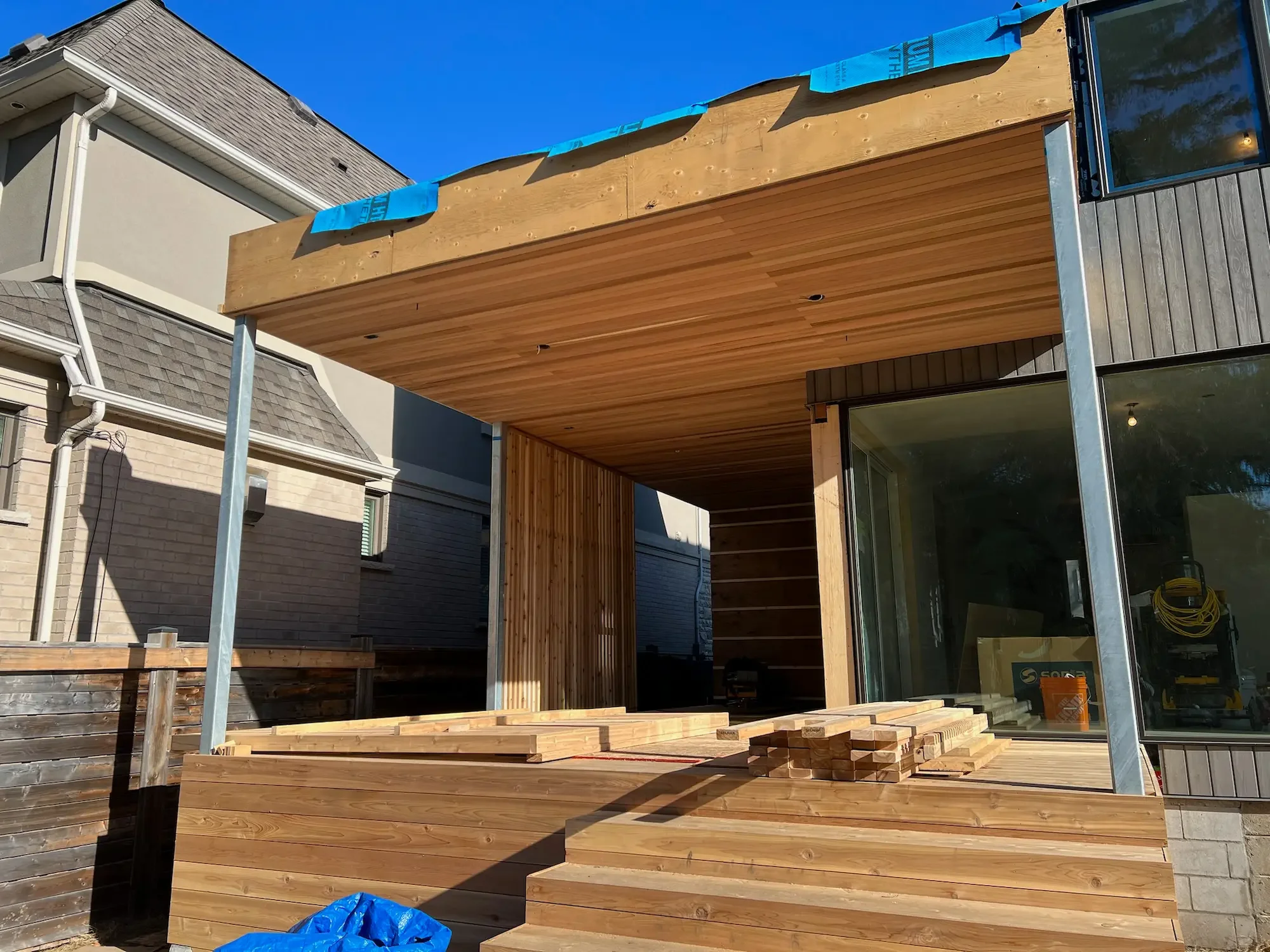 Covered deck with cedar ceiling, architectural privacy screen, and cedar steps at custom home in Etobicoke by Odin Agnuk