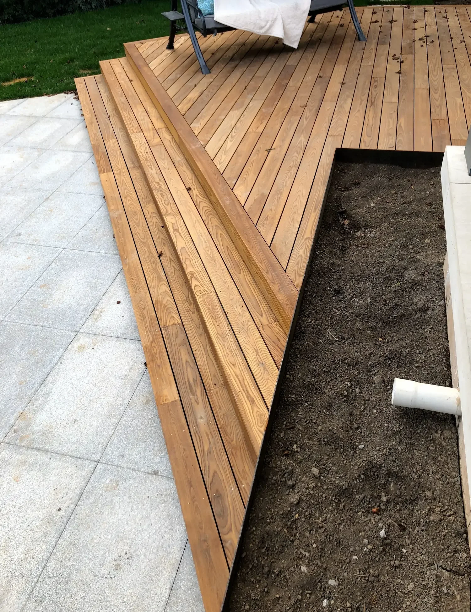 Thermory ash deck with angled stairs showing natural wood grain in Brant Hills by Odin Agnuk