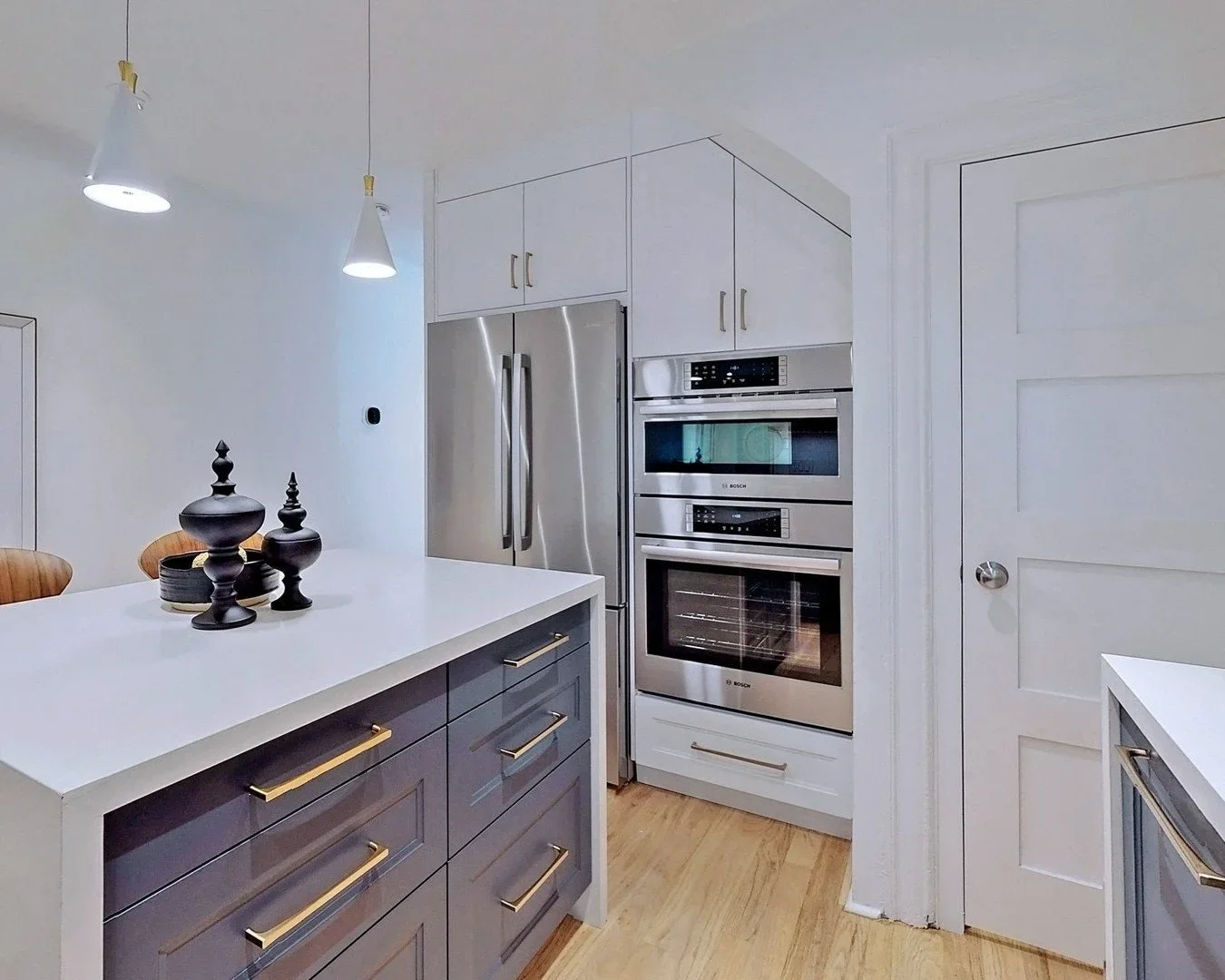 Kitchen with stainless steel appliances and built-in wall oven in Leslieville by Odin Agnuk