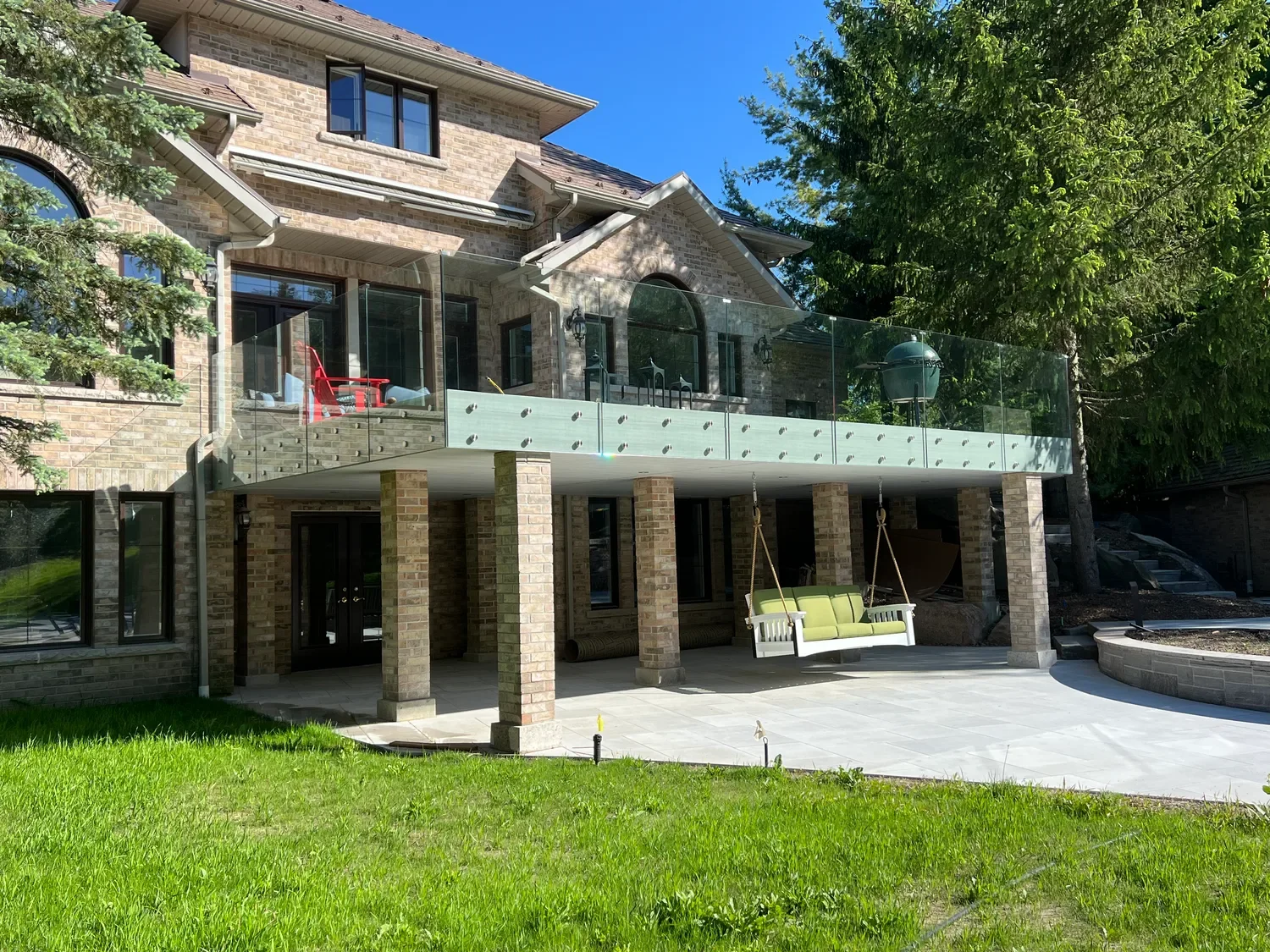 Odin Agnuk elevated deck with standoff-mounted glass railing panels providing unobstructed backyard views