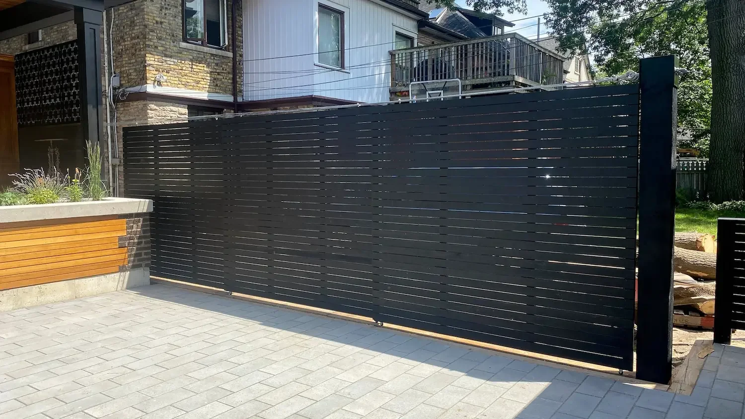 Black sliding horizontal slat privacy screen in closed position at Roncesvalles, Toronto home by Odin Agnuk