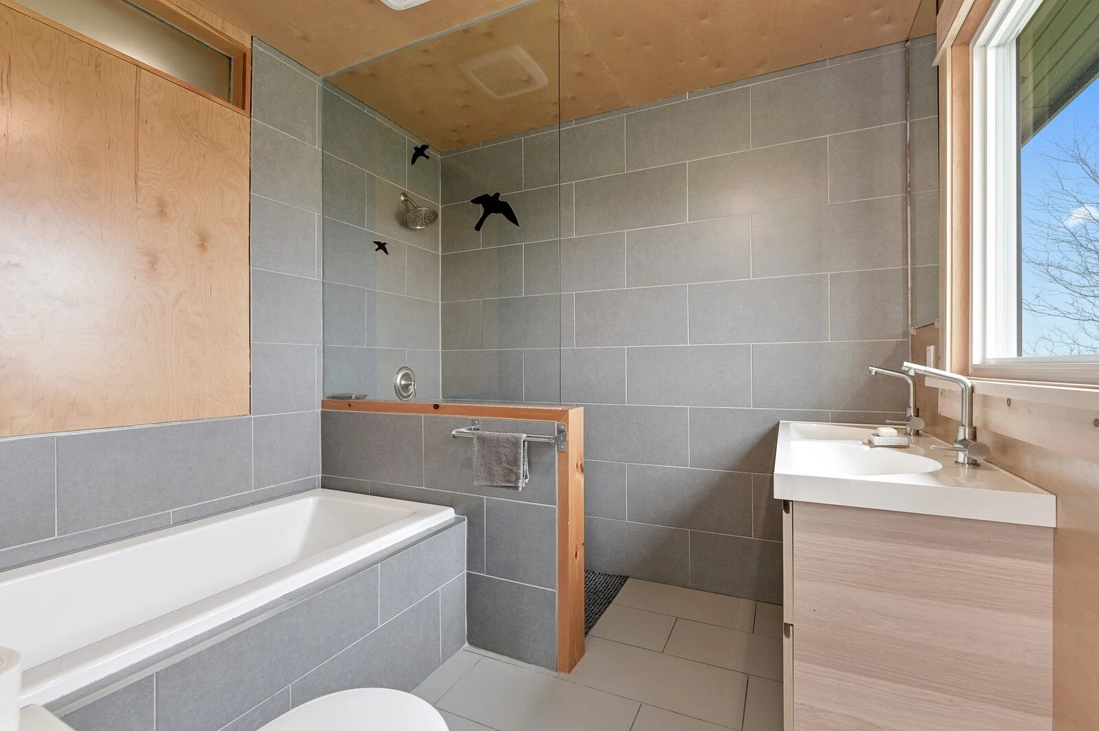 Bathroom renovation with grey tile, walk-in shower, soaking tub, and wood accents - Grey County by Odin Agnuk