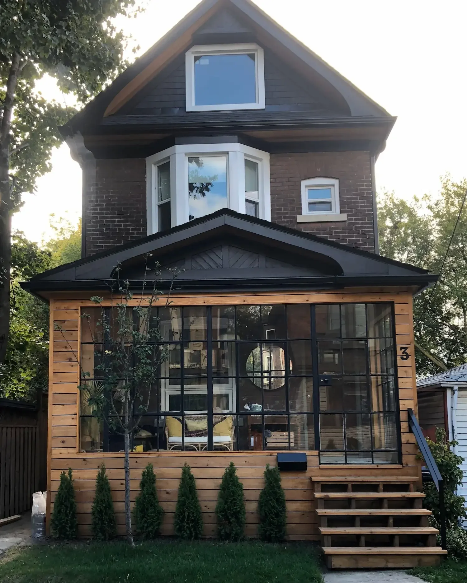 Enclosed porch addition with cedar siding and black steel windows on Victorian home - The Beaches Toronto by Odin Agnuk