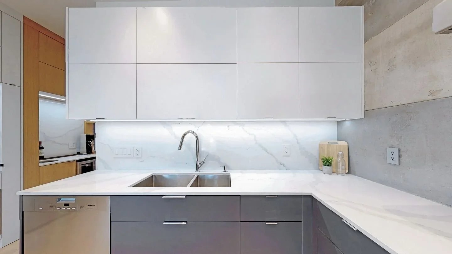 Kitchen with white upper cabinets marble backsplash and concrete wall at The Pocket by Odin Agnuk