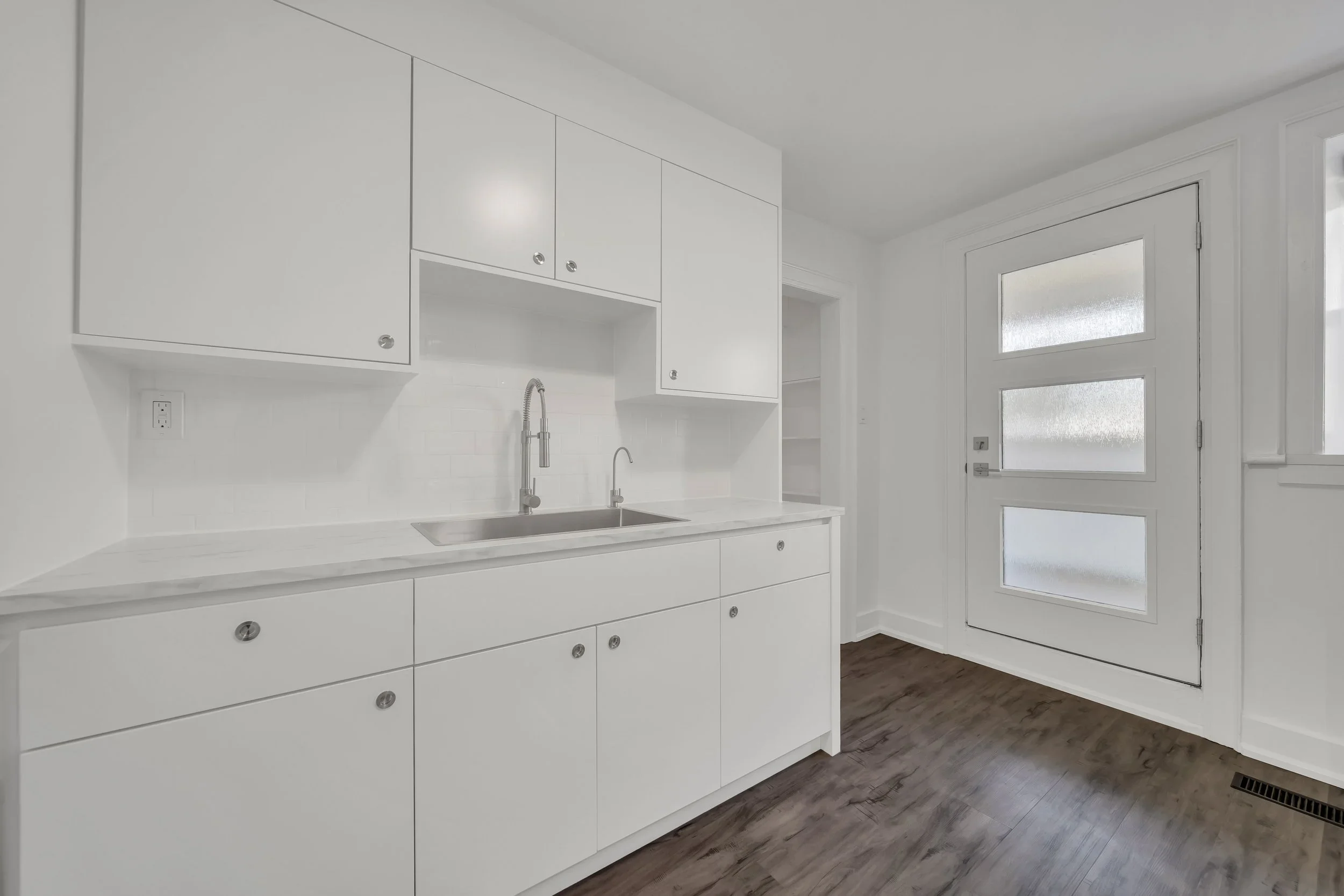 Galley kitchen with white cabinets and quartz countertop in Guelph duplex by ODIN+AGNUK