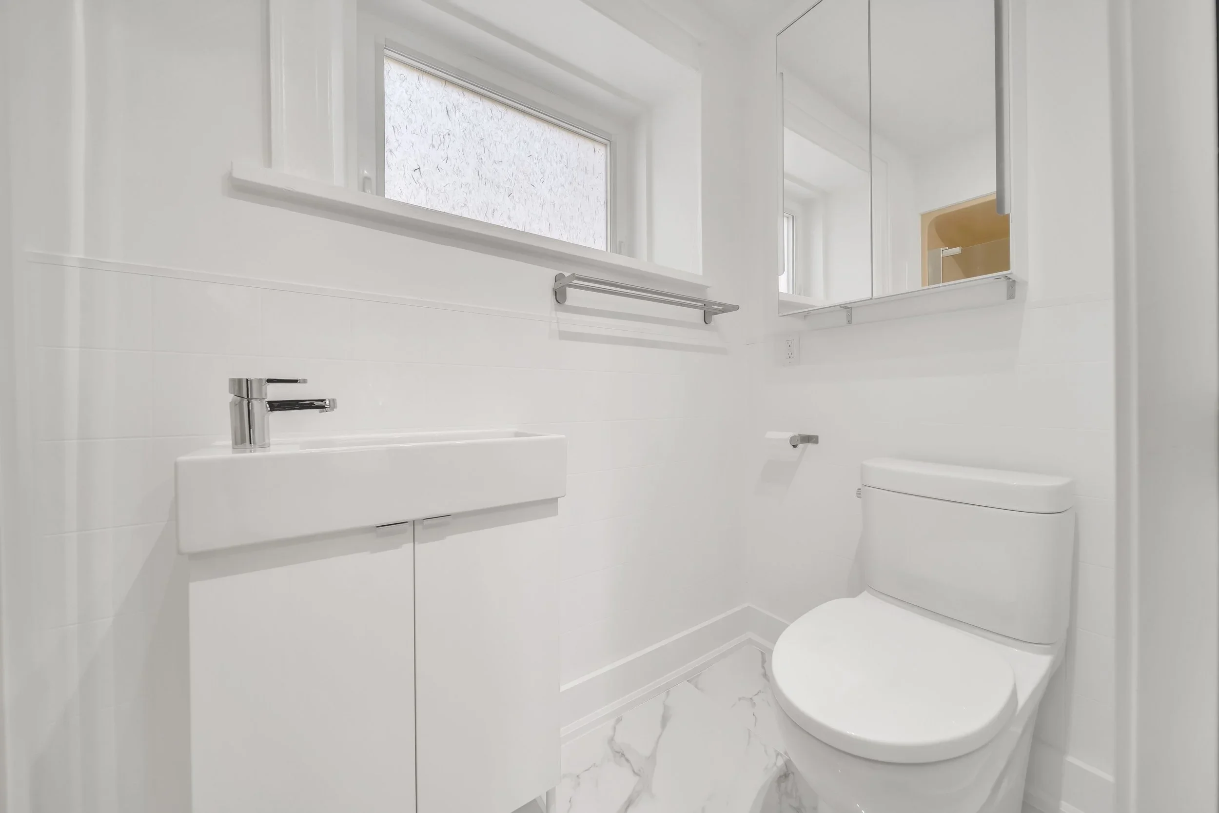 Modern powder room with vanity, medicine cabinet, and marble tile floor in Guelph renovation by ODIN+AGNUK