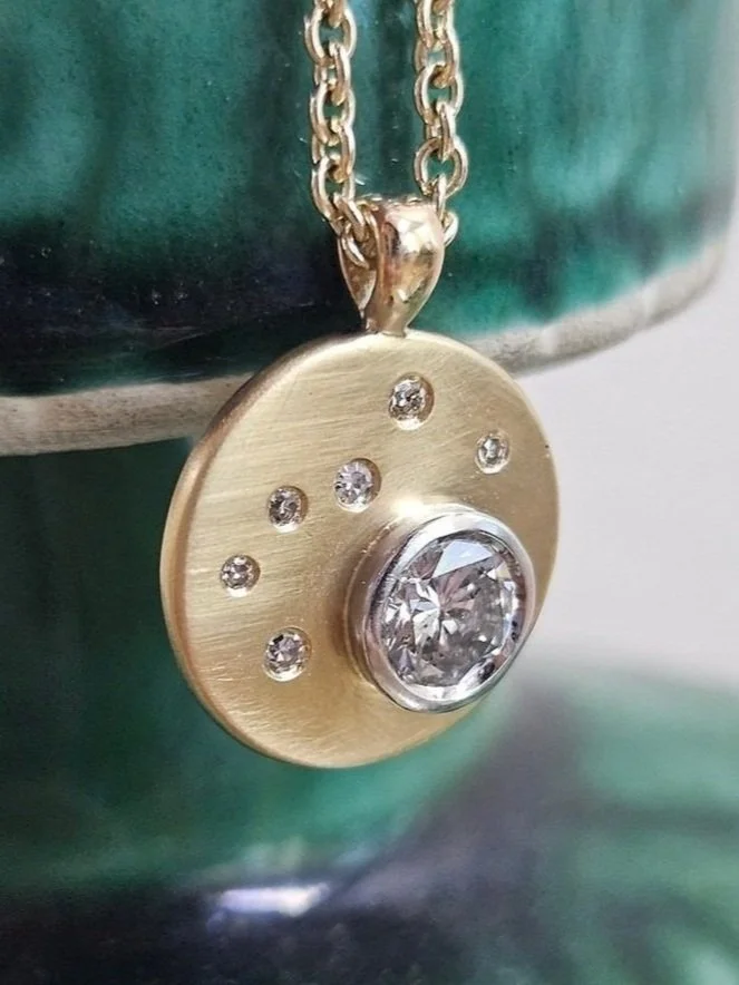 Close up of a gold necklace pendant with diamond gemstones