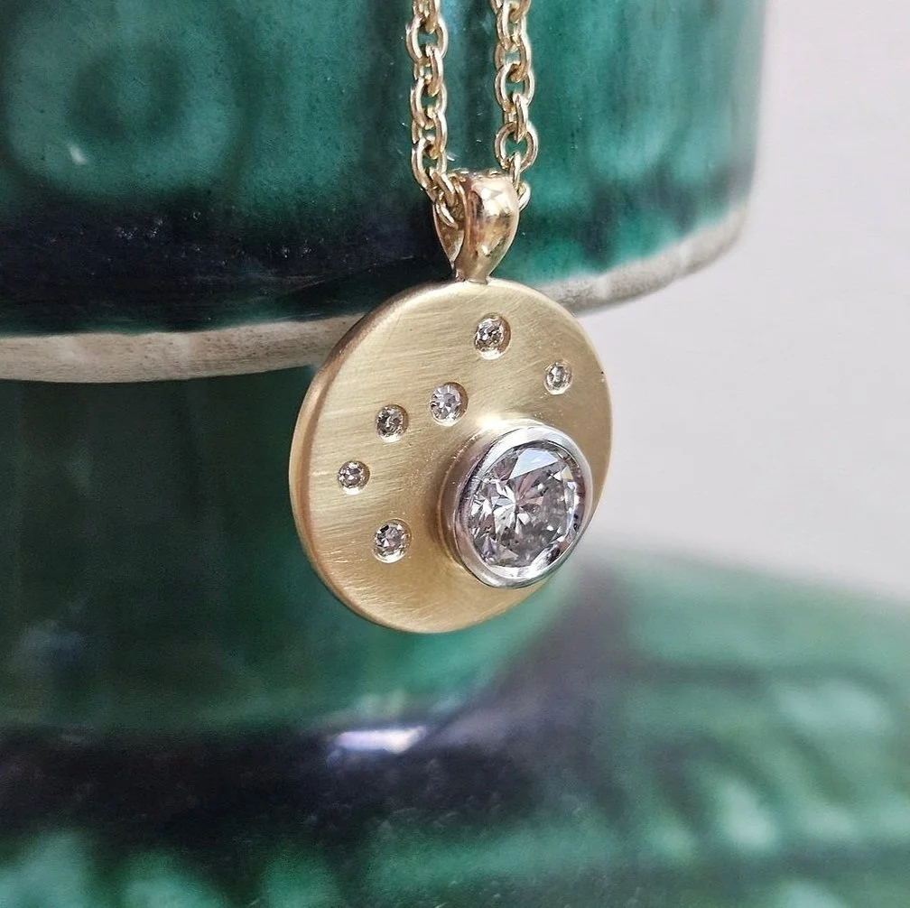 Close up photo of a diamond-studded gold necklace pendant on a gold chain