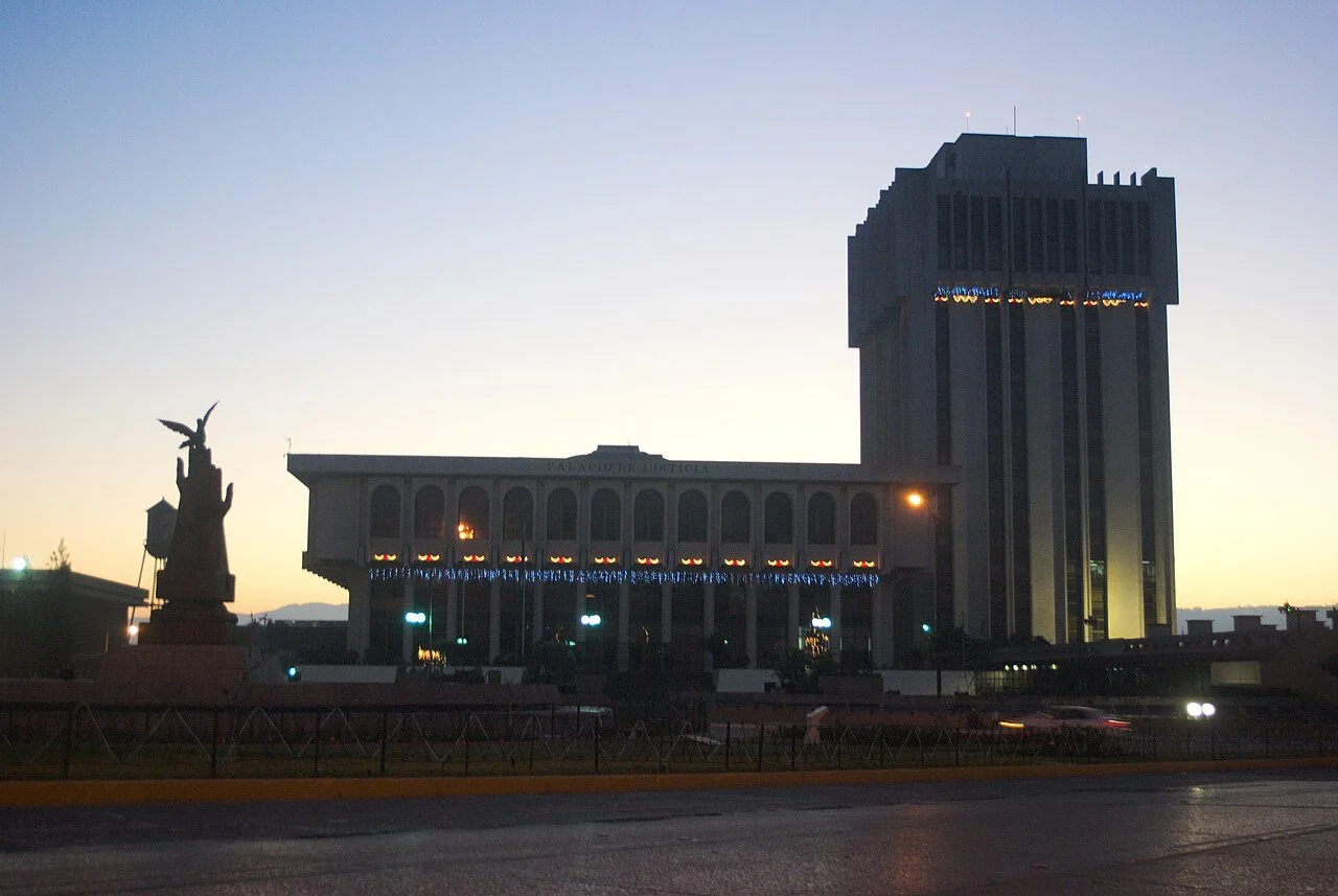 yellow and blue wide shot of  Guatemala Supreme Court and Monument to Peace at dawn. (Spanish: Palacio de la Justicia, Torre de Tribunales junto al Monumento a la Paz. Zona 1, Ciudad de Guatemala)
