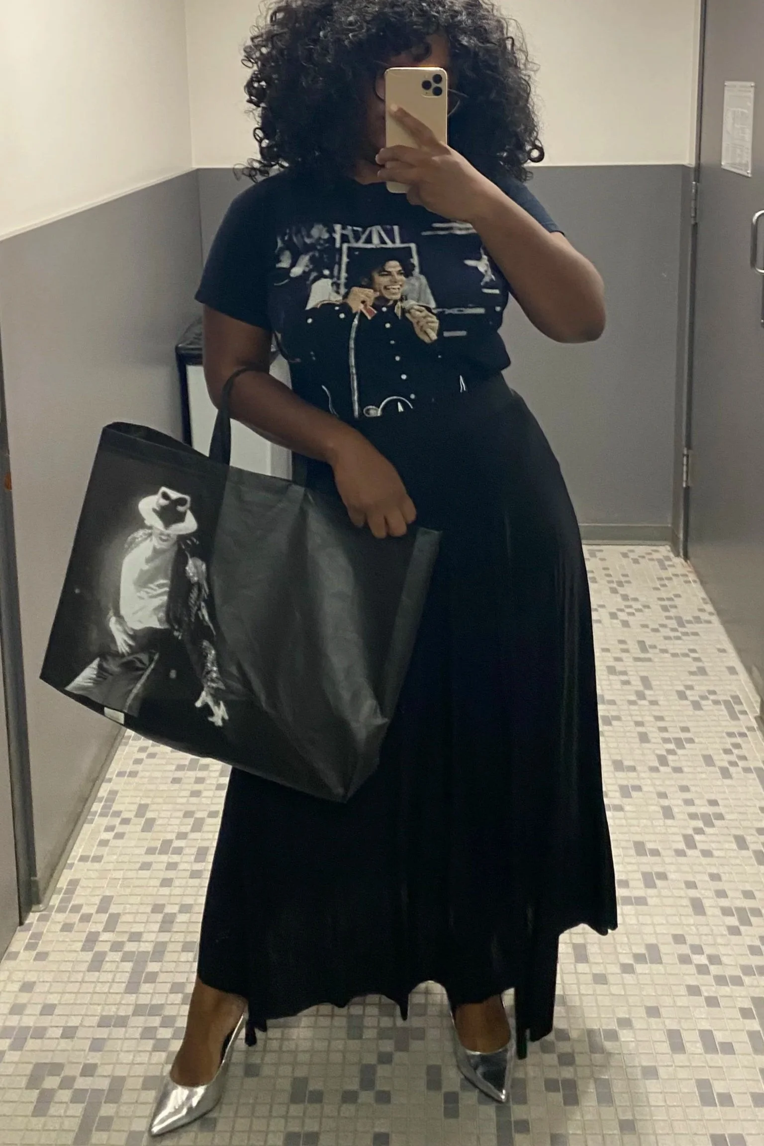 Black woman with curly hair  in Michael Jackson shirt and Michael Jackson bag