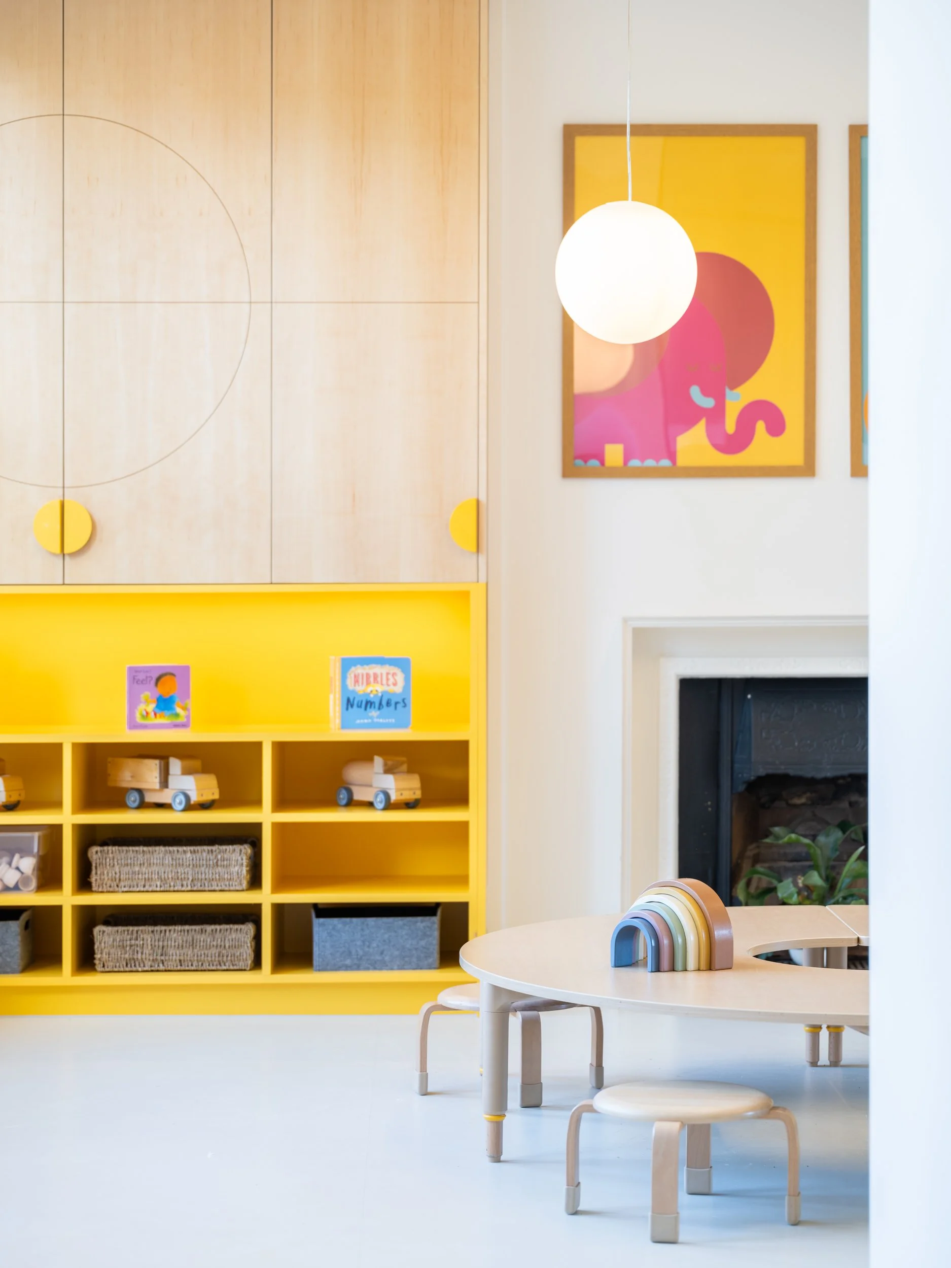 Early years learning interior with bold yellow storage joinery, child-sized furniture, and playful educational elements designed to support creativity, independence, and pupil-centred learning.