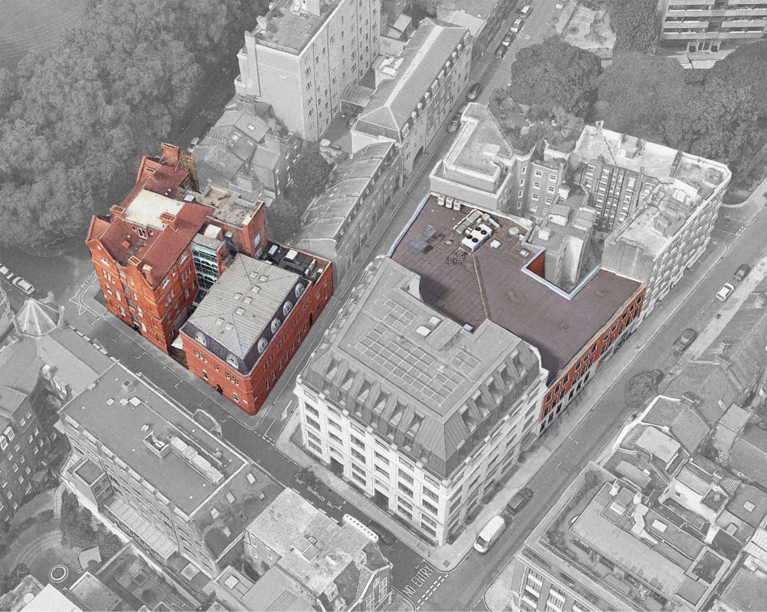 Aerial view of city buildings, with one prominent red brick building in the foreground and several gray high-rise buildings. Streets with cars and road markings are visible.