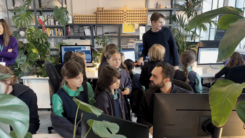 Animated scene of school children visiting a contemporary architecture and design studio, exploring computer workstations and creative workspace environments alongside architects and designers.