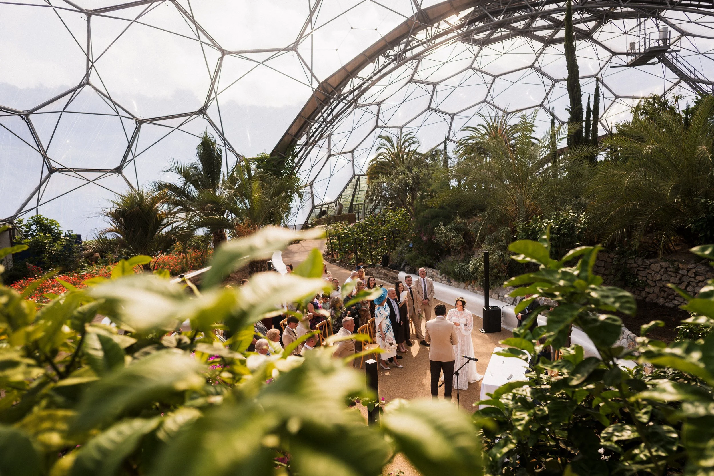Wedding ceremony surrounded by tropical plants inside a glass-domed greenhouse