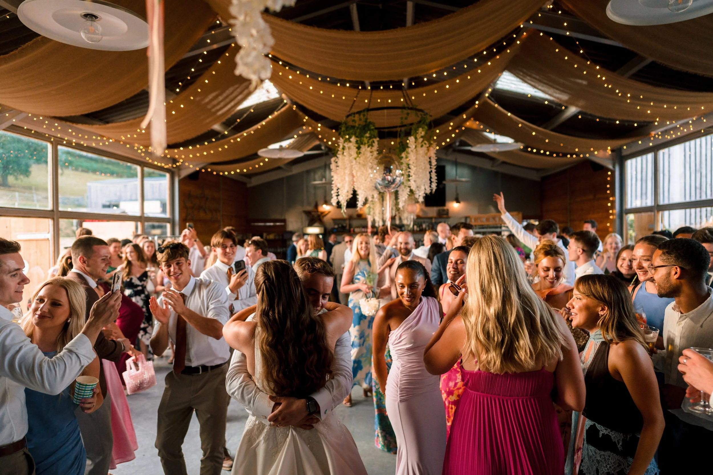 Wedding reception with guests dancing beneath draped fabric and string lights