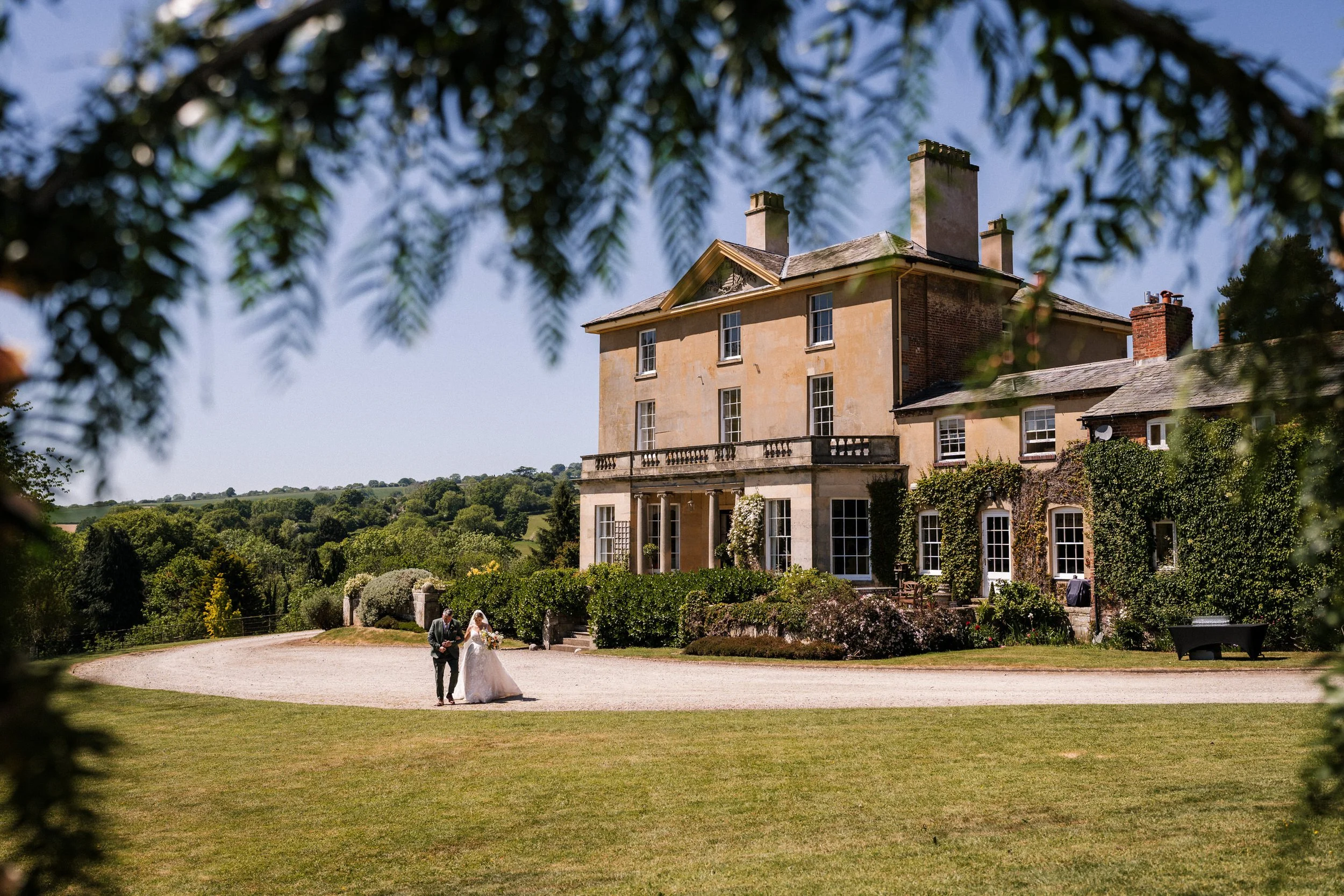 Bride and groom outside a historic country estate surrounded by gardens and countryside