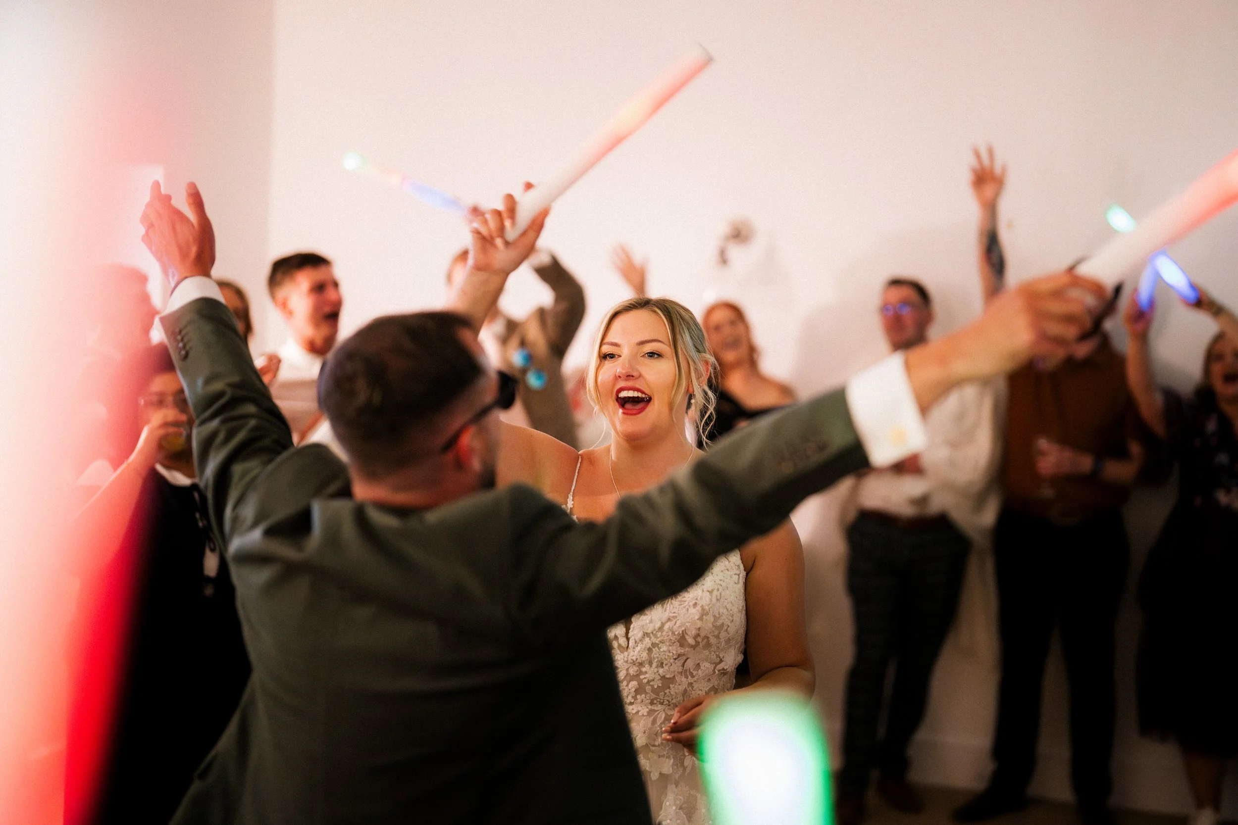 Bride smiling and dancing with wedding guests at a lively reception