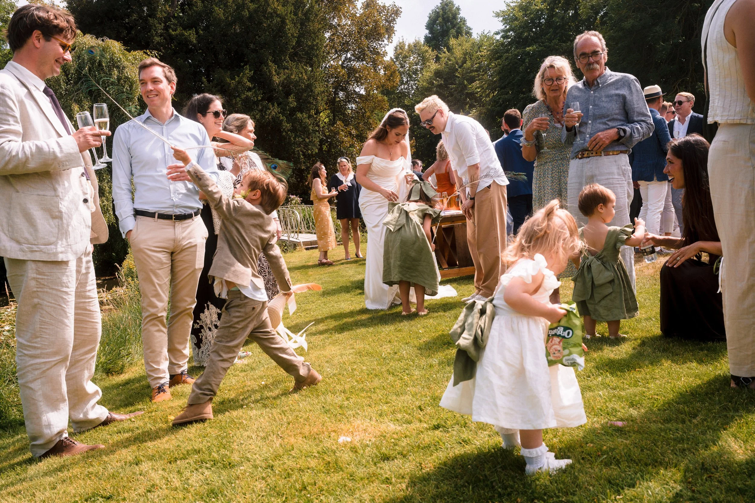 Wedding guests mingle and children play during an outdoor garden reception.