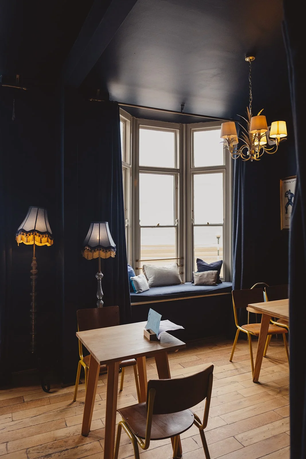 A dramatic blue room with a large windows looking out over Margate beach at the seafront. This is an image of Little Swift's upstairs room available for hire for your birthday.