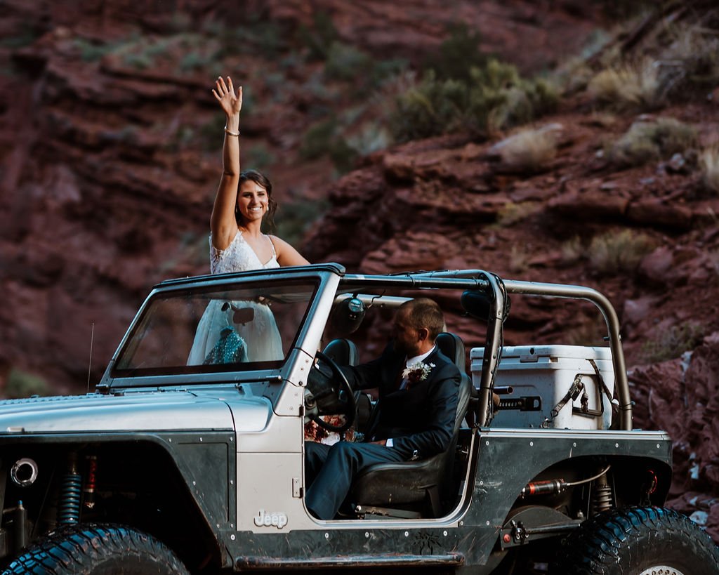 couple waves from jeep at moab elopement