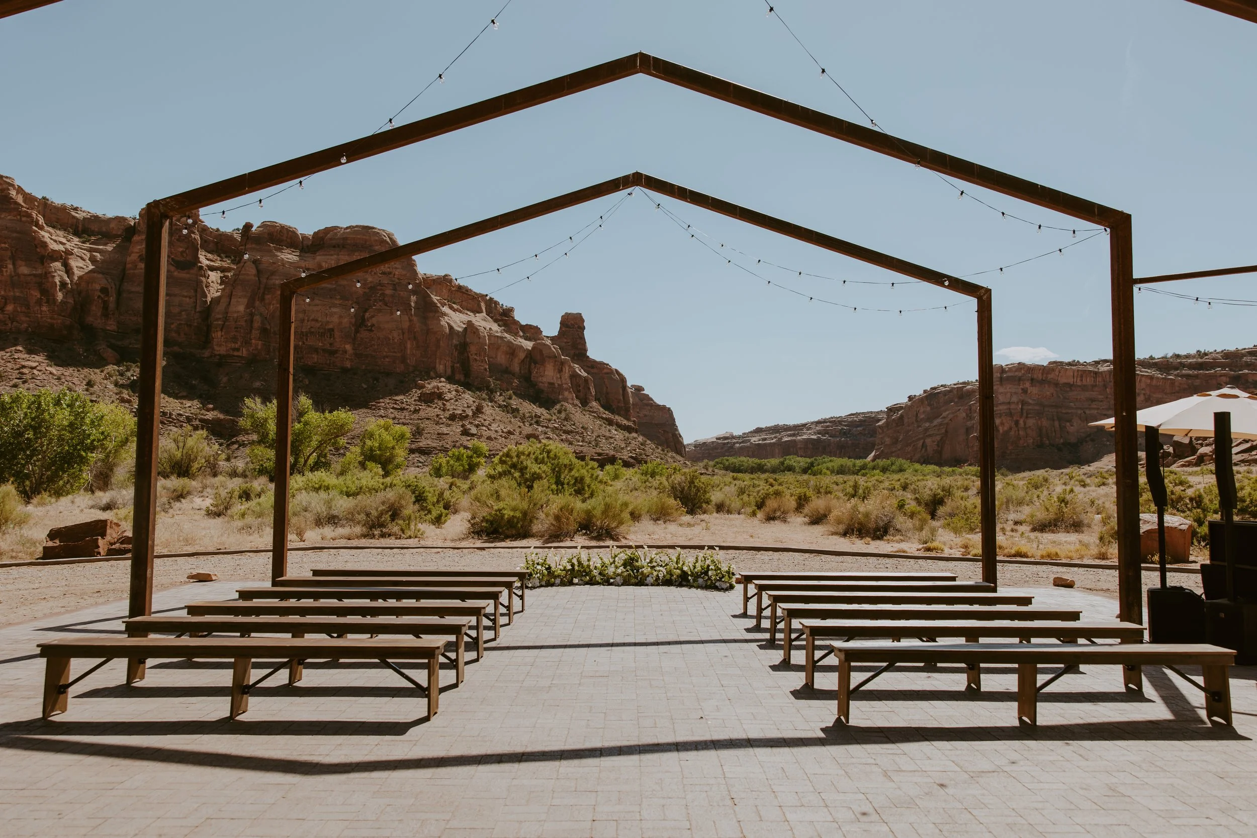 Outdoor wedding ceremony structure with string lights overlooking red rock cliffs at The Red Earth Venue in Moab, Utah