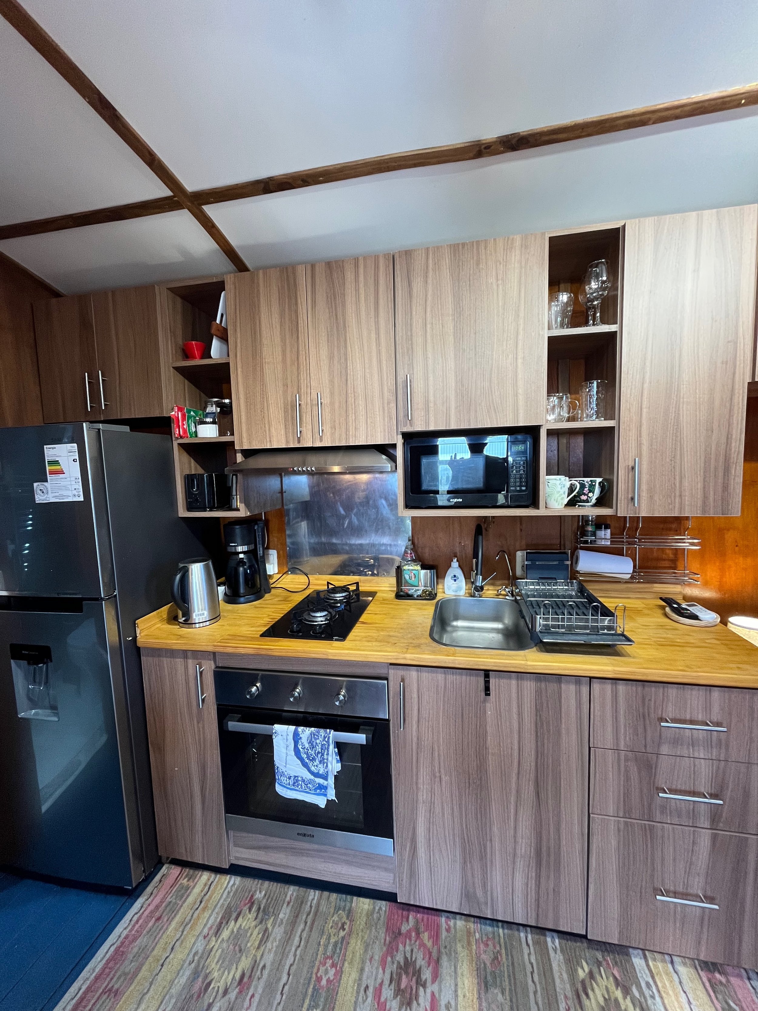 Kitchen with wood cabinets, stainless steel appliances, a gas stove, microwave, and a small sink with a dish rack.