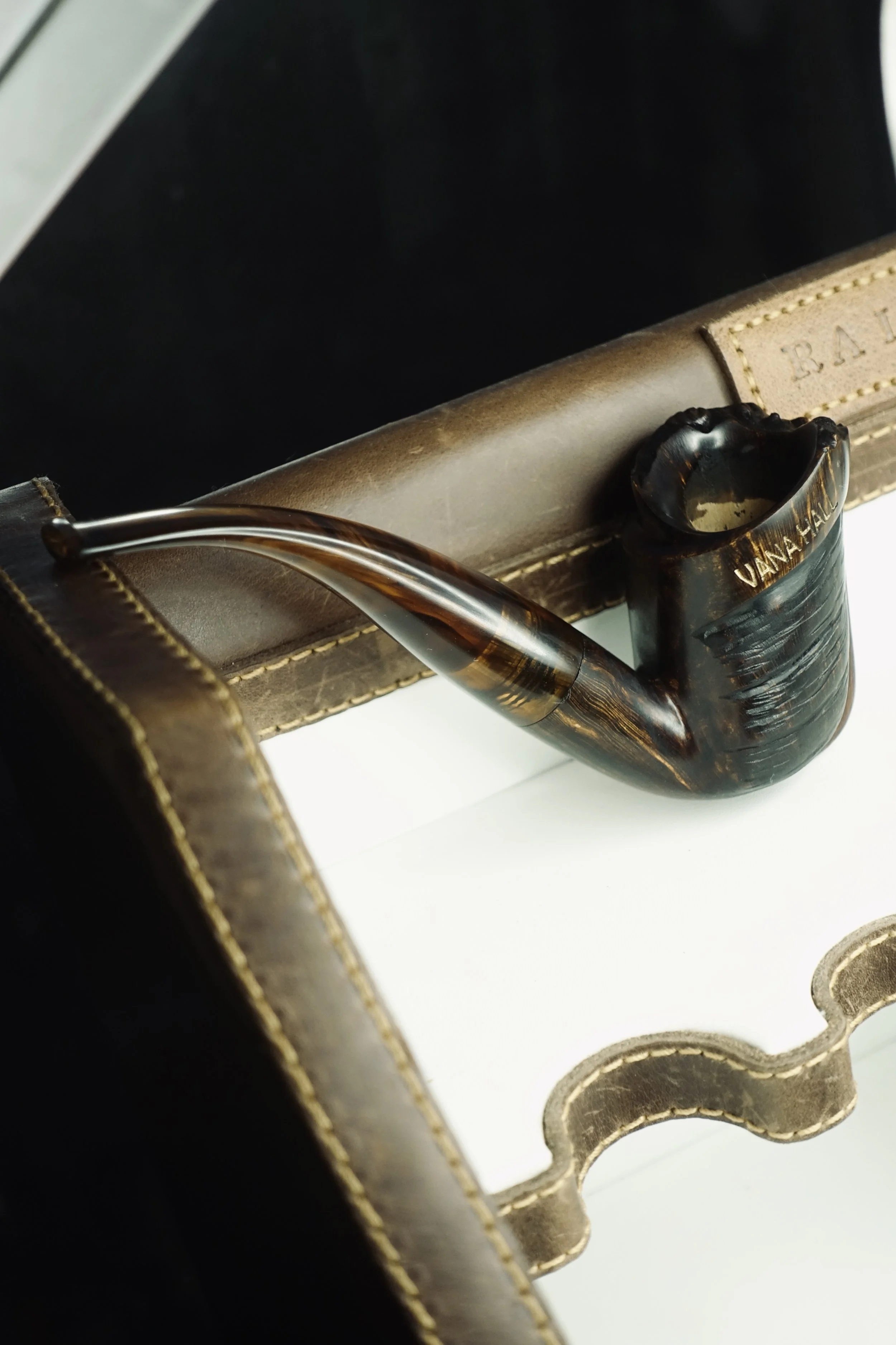A smoked pipe resting on a vintage leather case inside a display box.
