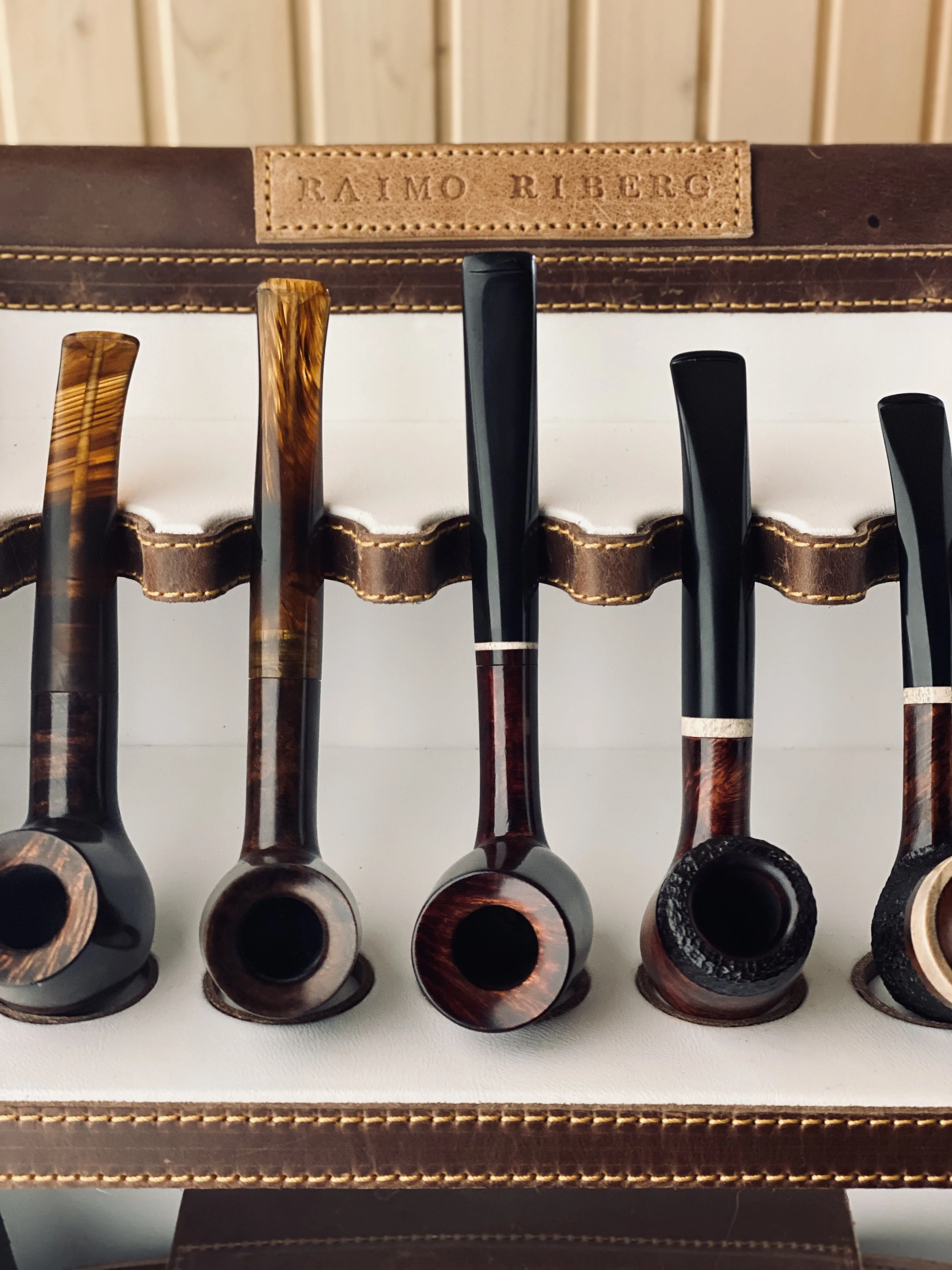 Collection of wooden smoking pipes displayed in a leather holder