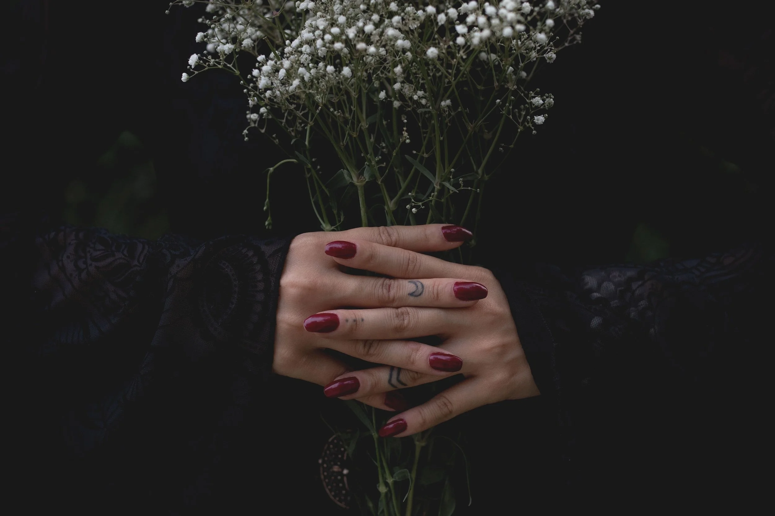 dark wine red manicured hands holding flowers by Fernanda Alves Pexels