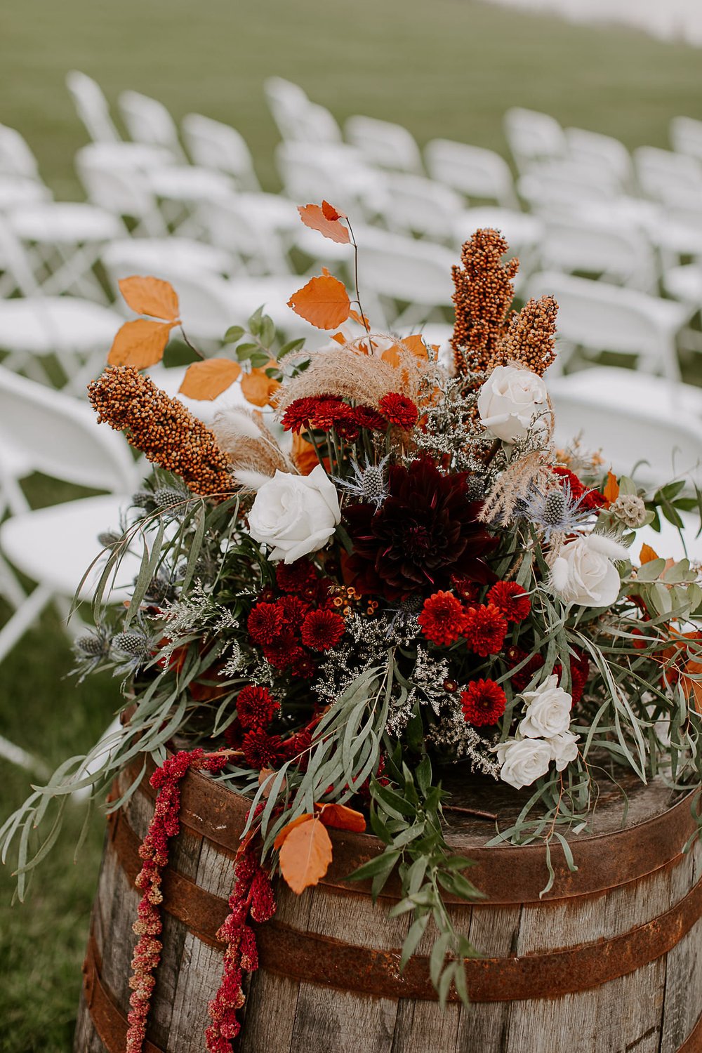 Fall wedding florals placed on barrel at outdoor wedding