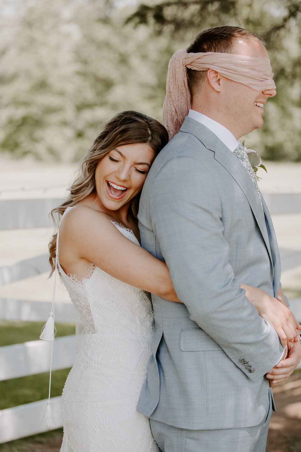 Bride embraces blindfolded groom during wedding first look